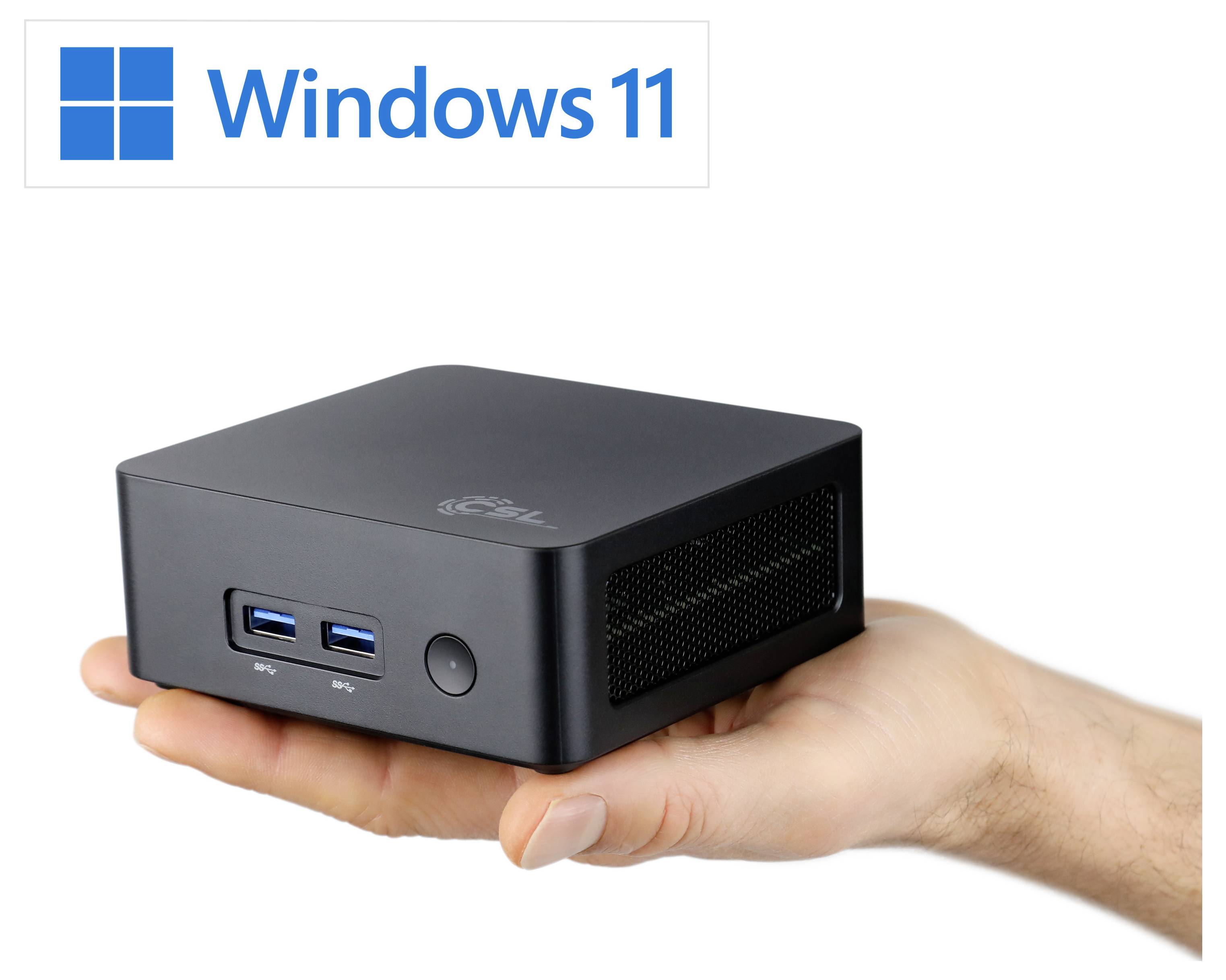 Lidská ruka drží malé černé zařízení s USB porty. Nad ním je viditelné logo 'Windows 11', které naznačuje kompatibilitu s tímto operačním systémem.