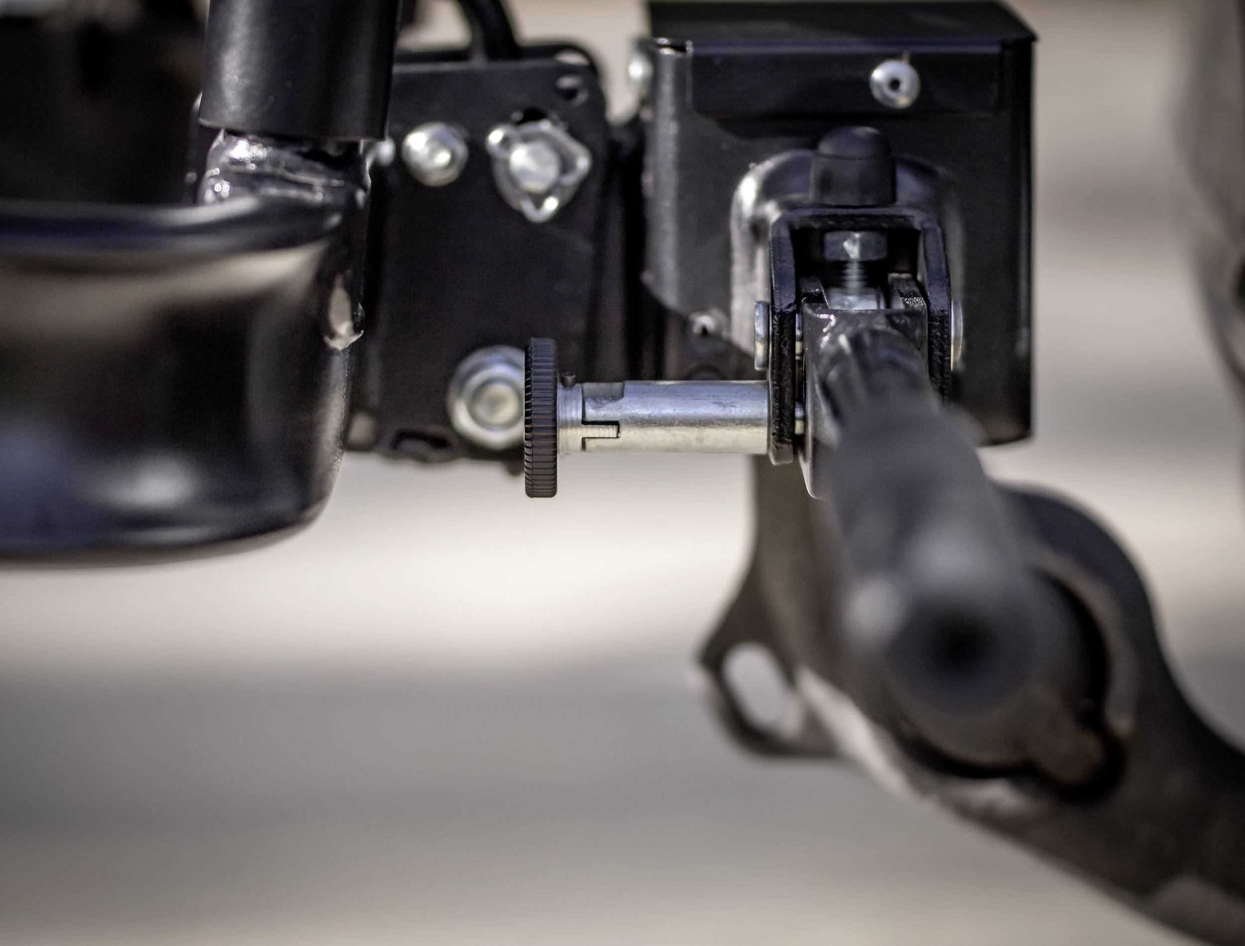 Detailní záběr mechanického zařízení s kovovým kolíkem, spojeným s černým pouzdrem. Bod vystřižený na rozmazaném pozadí.
