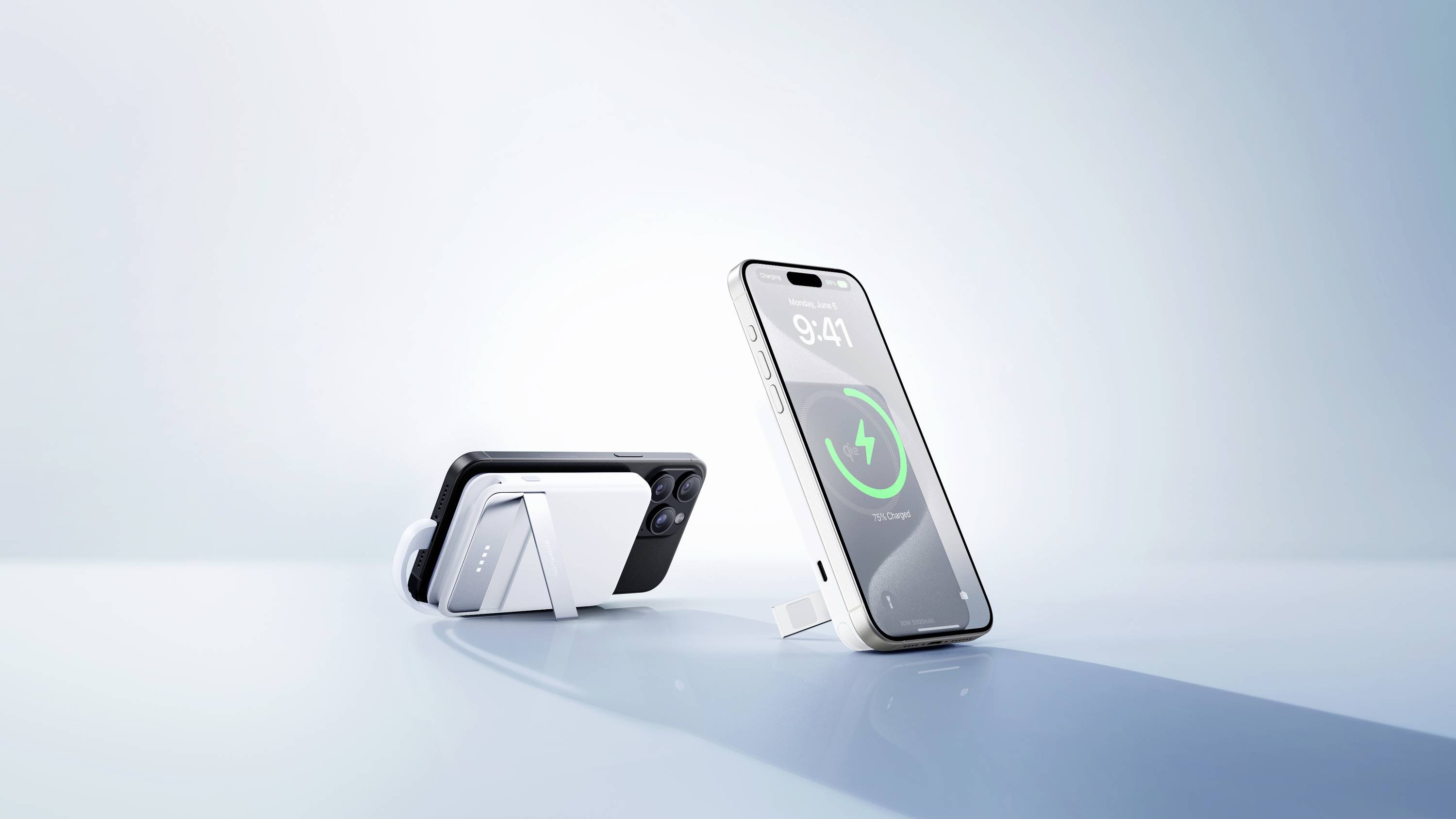 Dva moderní smartphony v průhledných obalech jsou umístěny na stole; jeden z nich zobrazuje indikátor nabíjení se zeleným symbolem.