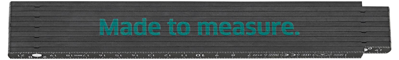 Skládací metr s nápisem 'Made to measure.', symbolizuje přesnost a přizpůsobivost.