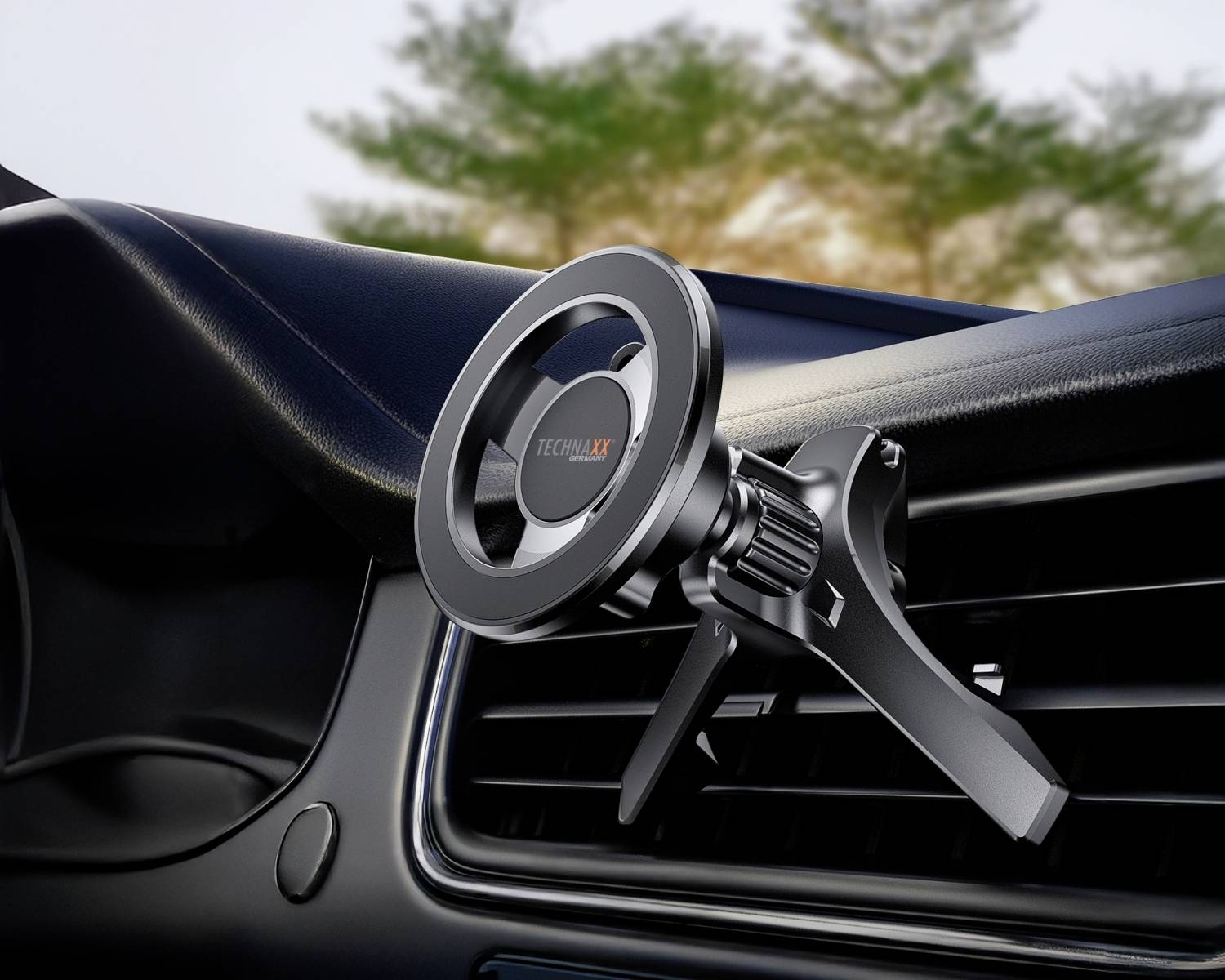 Držák na mobilní telefon je připevněn k ventilační mřížce automobilu. Design působí moderně a funkčně. V pozadí jsou viditelné stromy.