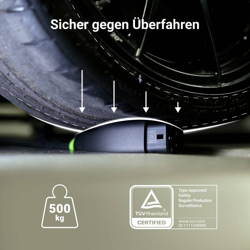 'Kabelový chránič pod pneumatikou automobilu se šipkami směřujícími dolů. Text: Bezpečný proti přejetí, 500 kg, certifikováno TÜV.'