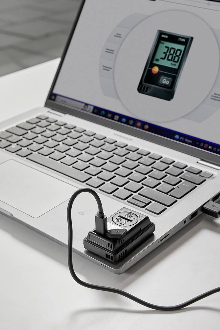 Laptop zobrazuje displej s hodnotami CO2. Měřicí zařízení je připojeno k laptopu a ukazuje hodnotu CO2 380 ppm.
