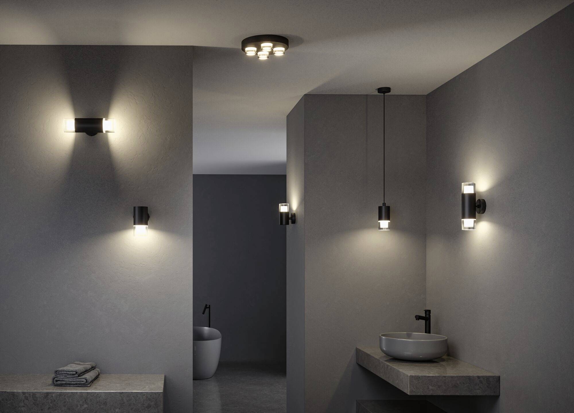 Moderní koupelnové osvětlení s několika nástěnnými a závěsnými svítidly, šedé stěny a minimalistický design s umyvadlem.