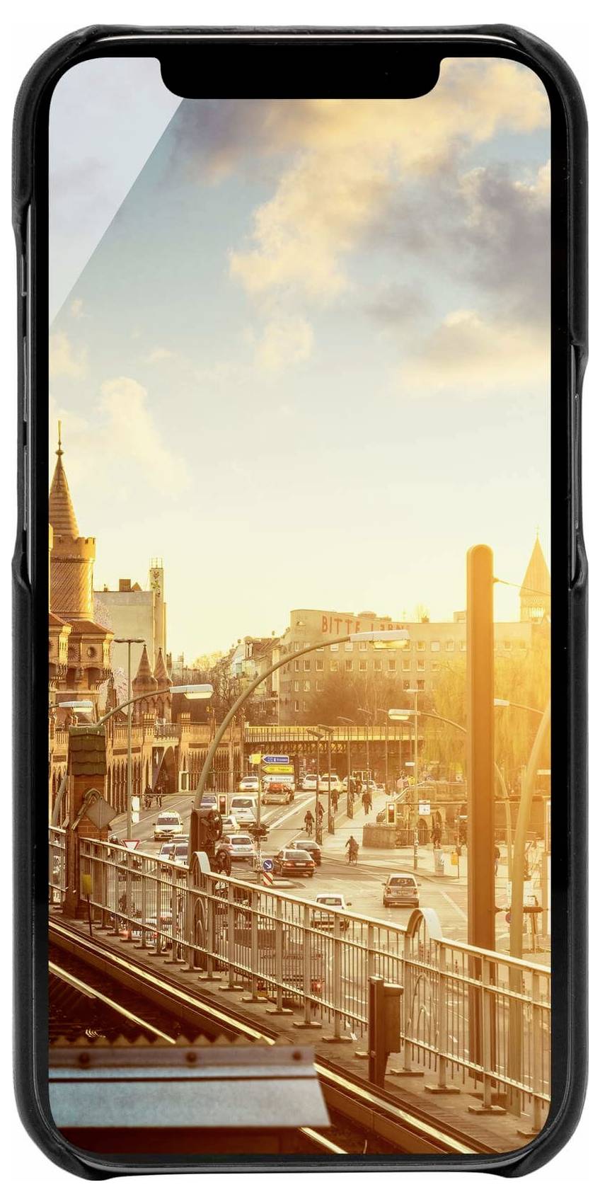Smartphone zobrazuje pohled na město při západu slunce. V popředí je vyvýšená silnice s auty, v pozadí historické budovy a mraky.