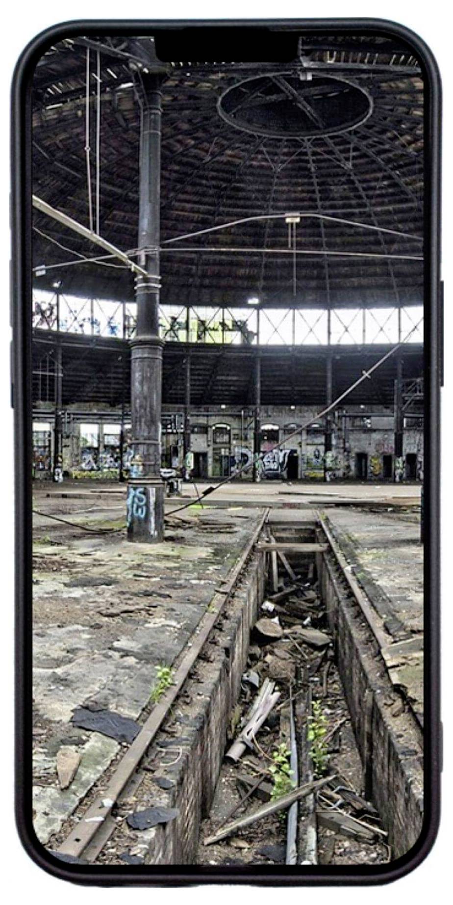 Stará, opuštěná tovární budova s výrazně poškozenými podlahami a graffiti na stěnách. Rostliny rostou mezi rozbitými dlaždicemi.