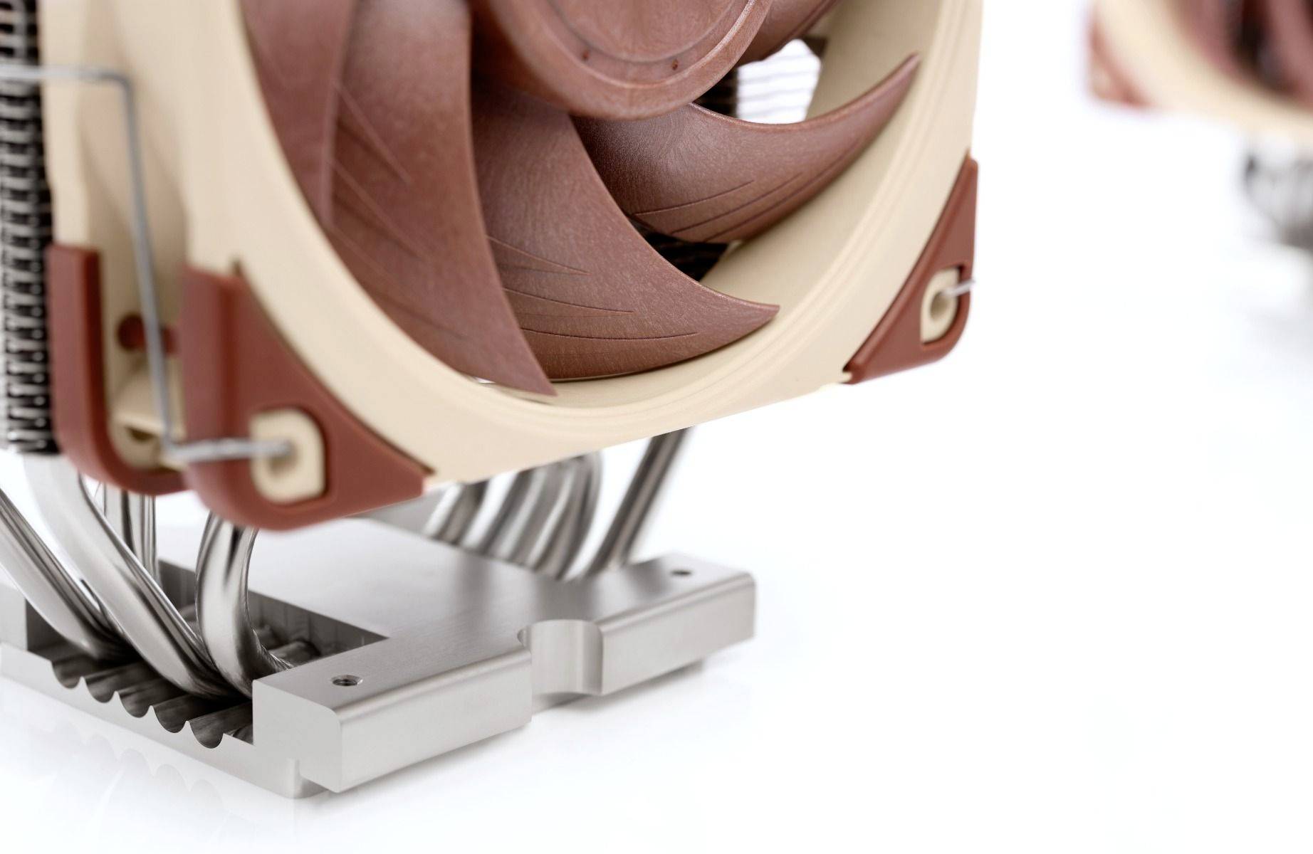 Detailní záběr chladiče procesoru s žebry a ventilátorem, namontovaný na kovovém podkladu.