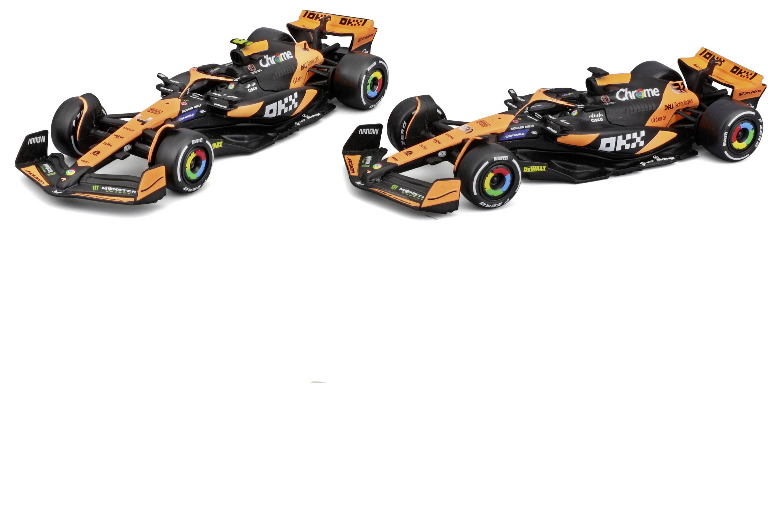 Dva oranžové a černé formulové vozy, zaparkované vedle sebe, zobrazující loga sponzorů a aerodynamické prvky designu, na jednoduchém pozadí.