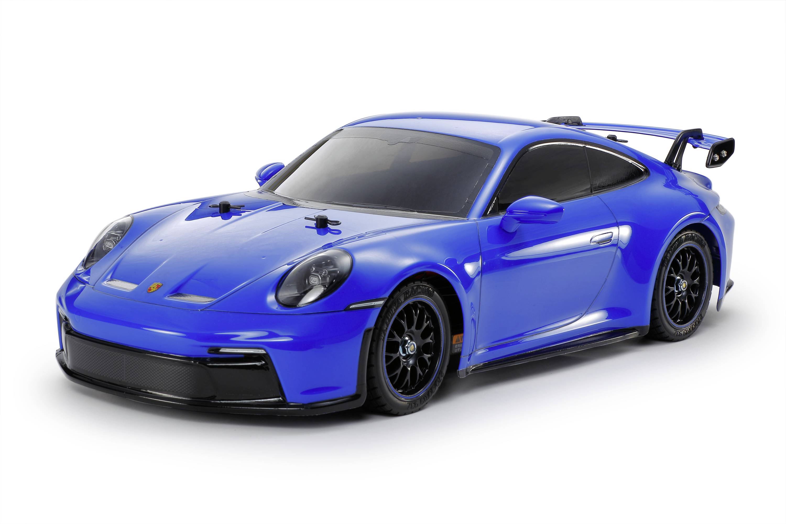 Modrý sportovní vůz s aerodynamickým designem a černým spoilerem, zaparkovaný na rovné ploše.