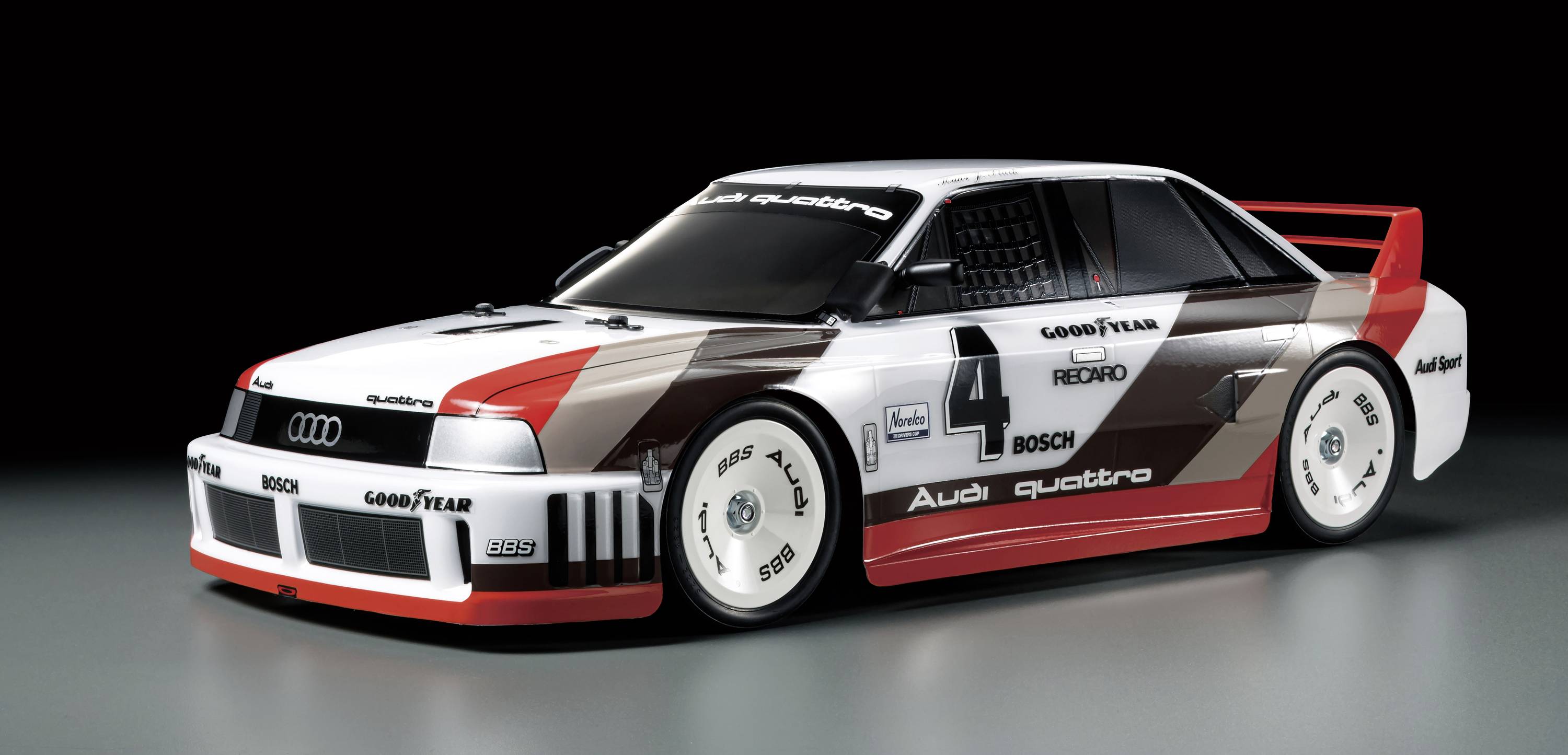 Závodní vůz s číslem 4, navržený v klasickém stylu Audi Quattro, stojí na tmavém povrchu.