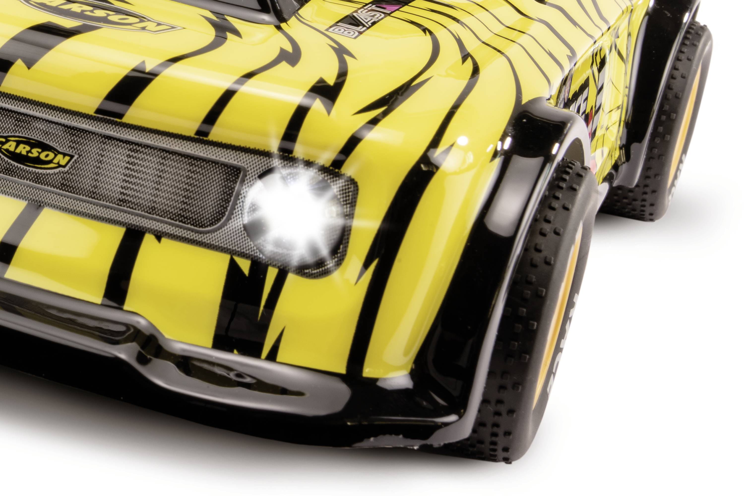 RC-auto v žluto-černém tygřím vzoru s osvětlenými světlomety, detailní záběr přední části a blatníku.