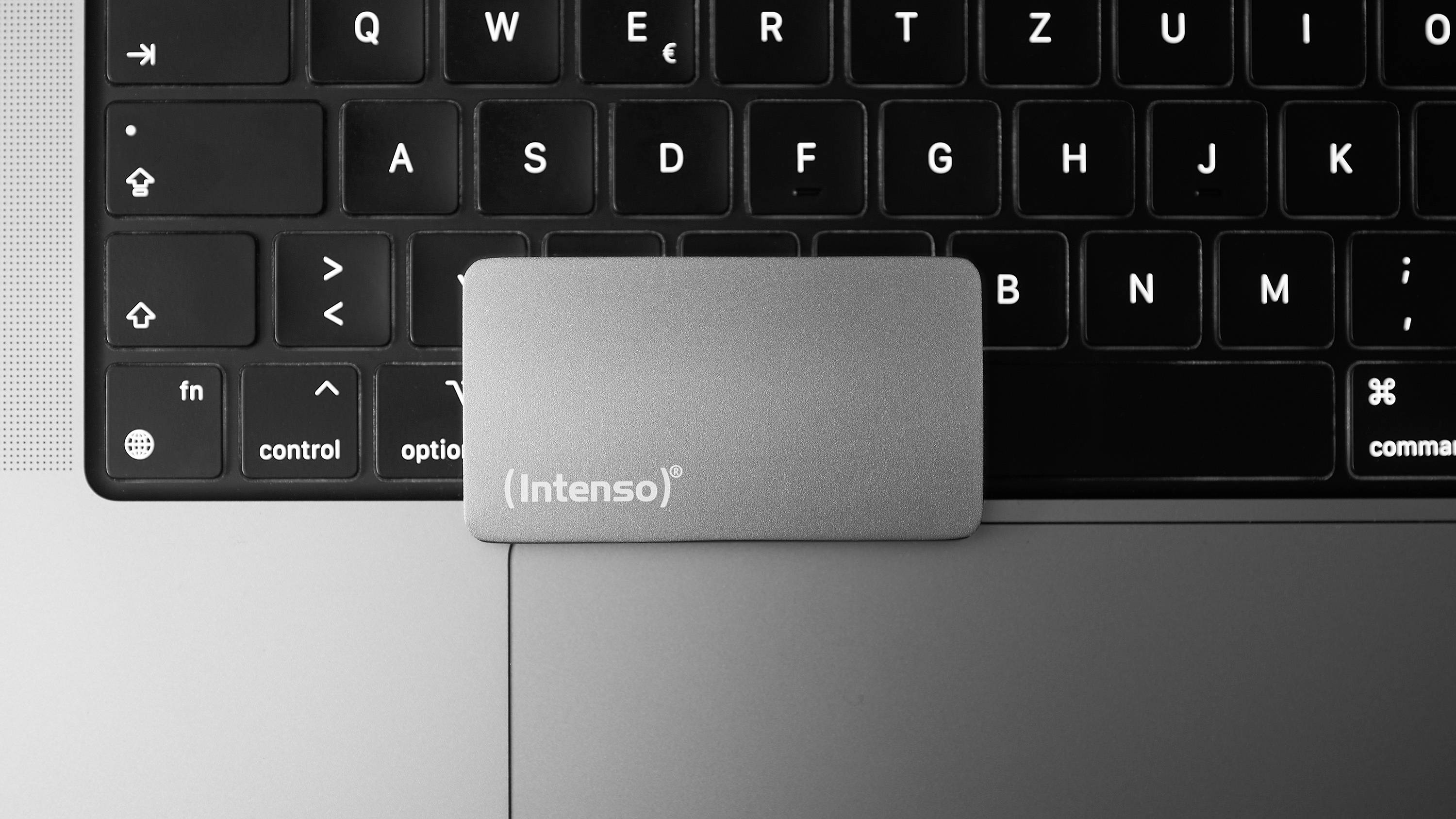 Externí disk 'Intenso' leží na klávesnici notebooku.