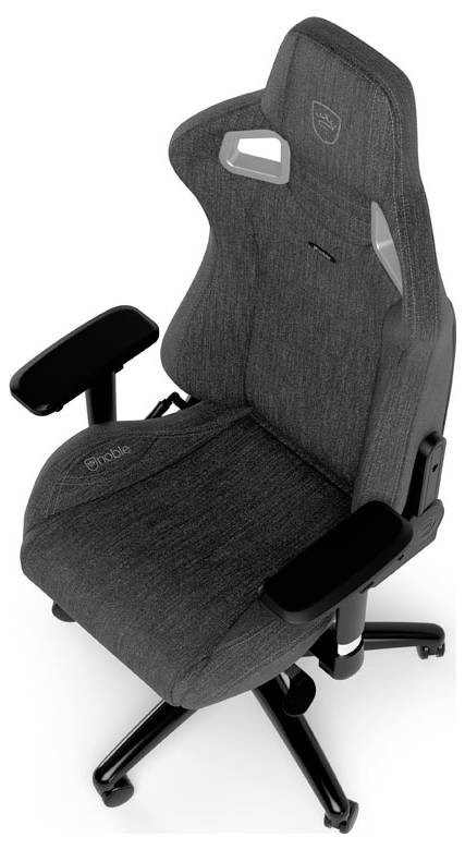 Šedá herní židle s ergonomickým tvarem, vysokým opěradlem a nastavitelnými opěrkami rukou. Ideální pro pohodlné sezení při dlouhém hraní.