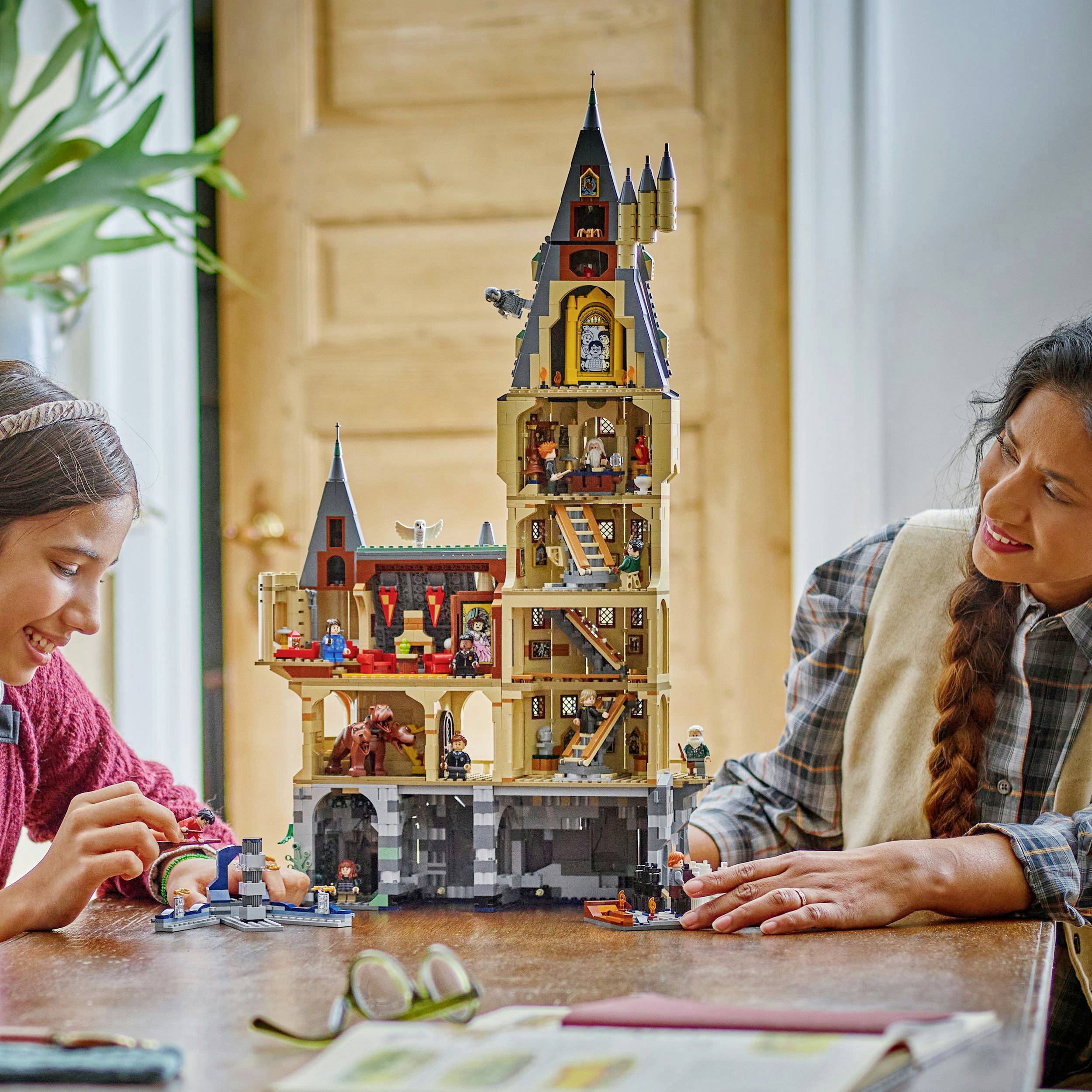 Dítě a dospělý člověk společně staví lego hrad na stole v útulném prostředí, usmívají se a soustředěně pracují.