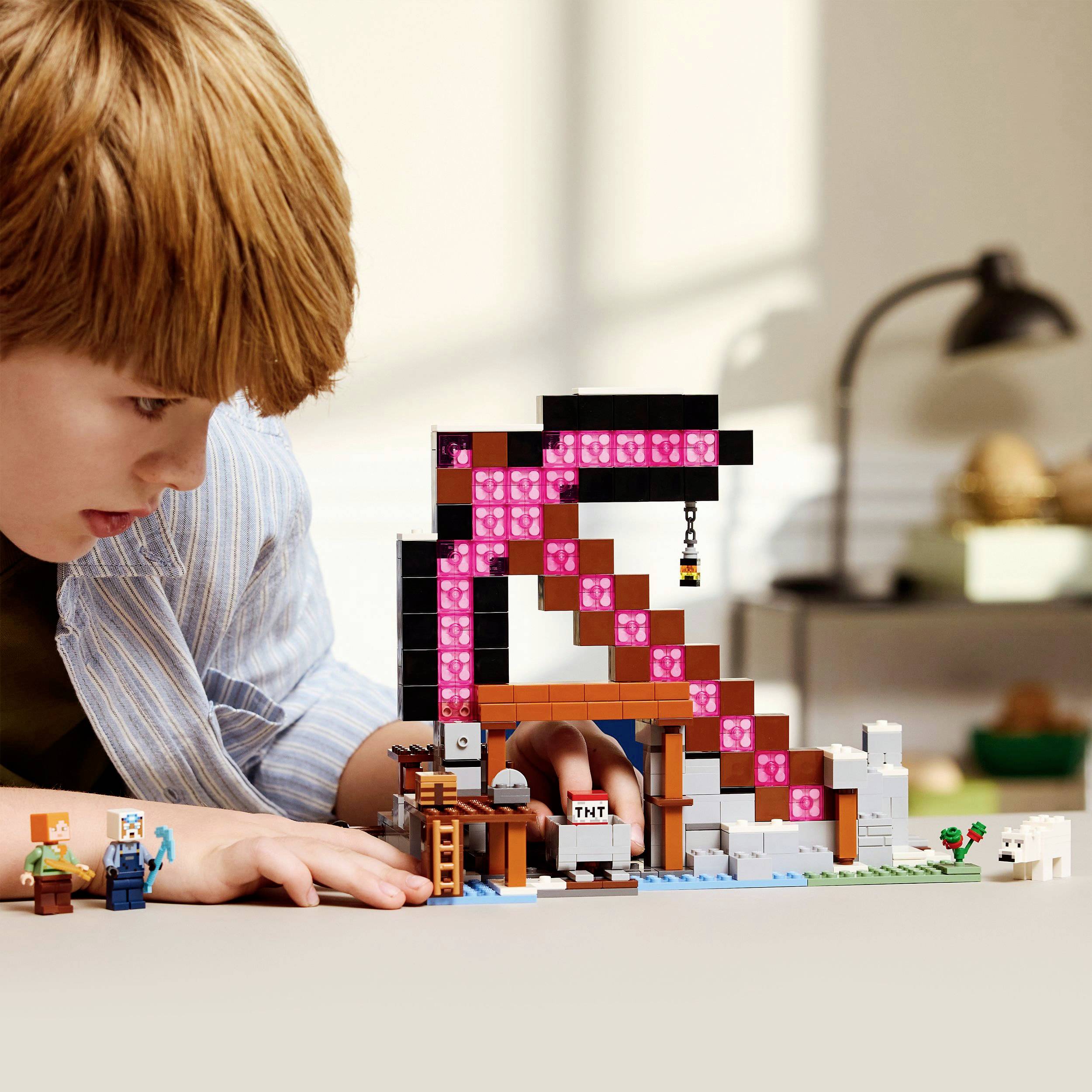 Dítě si hraje s kostkami Minecraft; krumpáč je výrazně a barevně zobrazen. V pozadí jsou viditelné detaily pokoje.