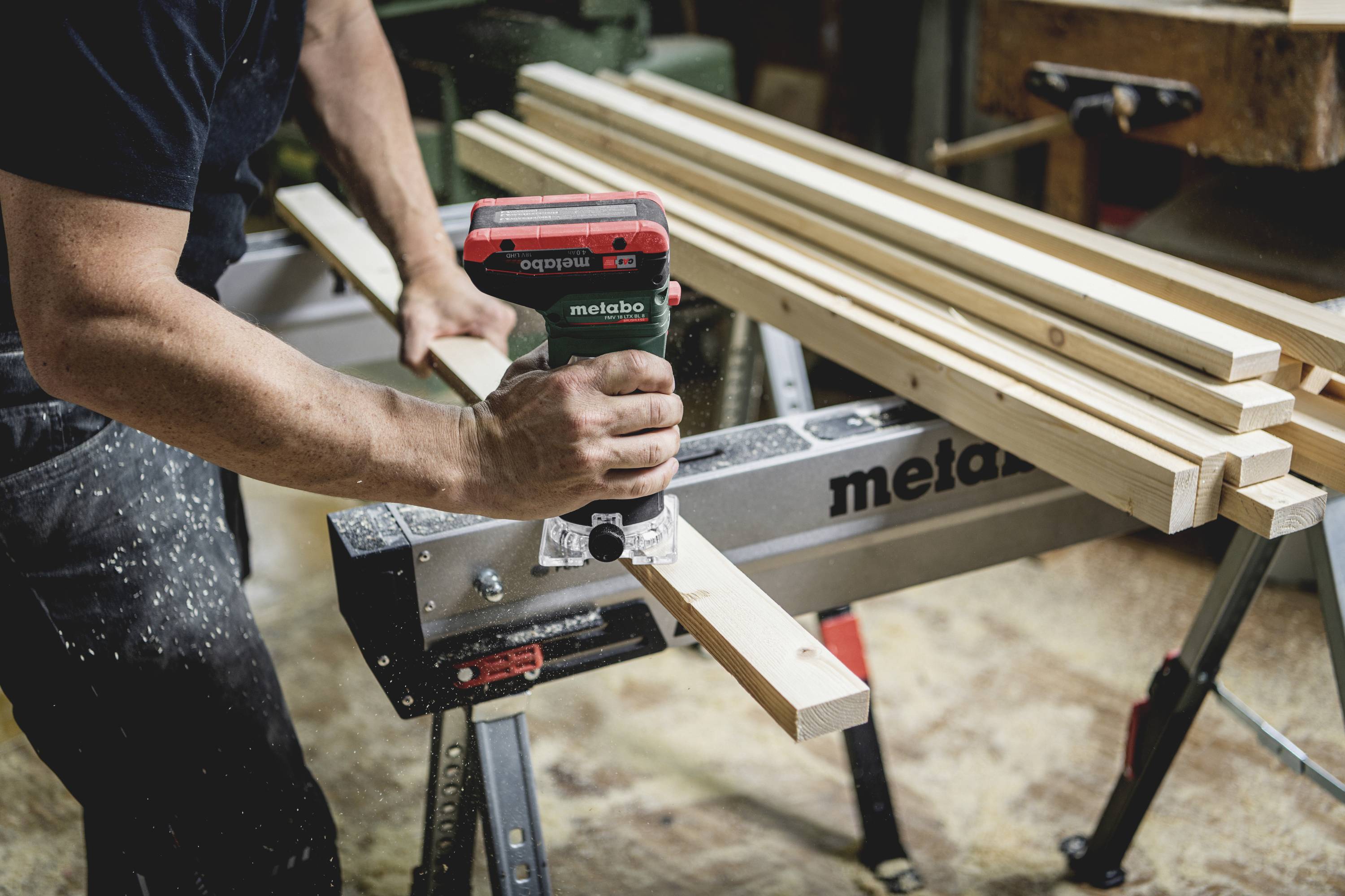 Řemeslník řeže dřevěné latě elektrickou pilou na pracovním stole v dílně.