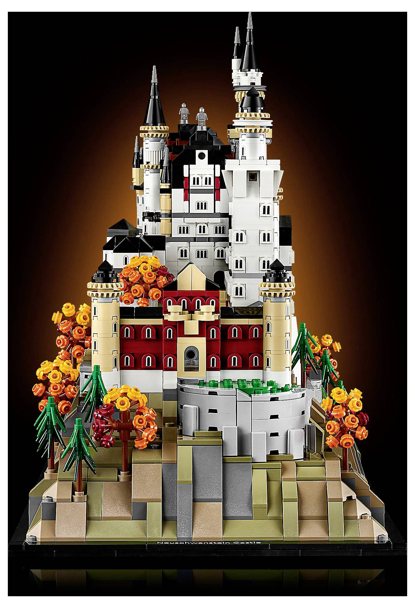 Detailní Lego model pohádkového zámku s vysokými věžemi, propracovanou architekturou a barevnými stromy na skalnatém podstavci.