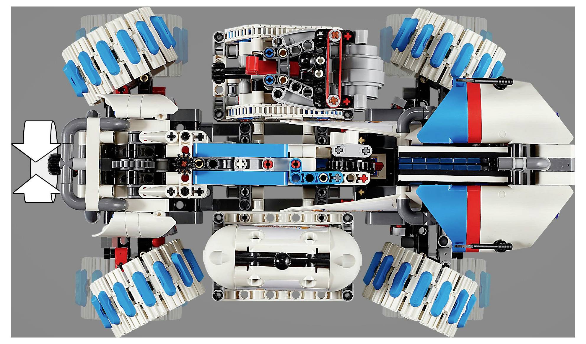 Pohled shora na vozidlo z LEGO kostek se čtyřmi velkými koly, v modro-bílém barevném provedení, s detailními mechanickými sekcemi a šipkovými značkami.