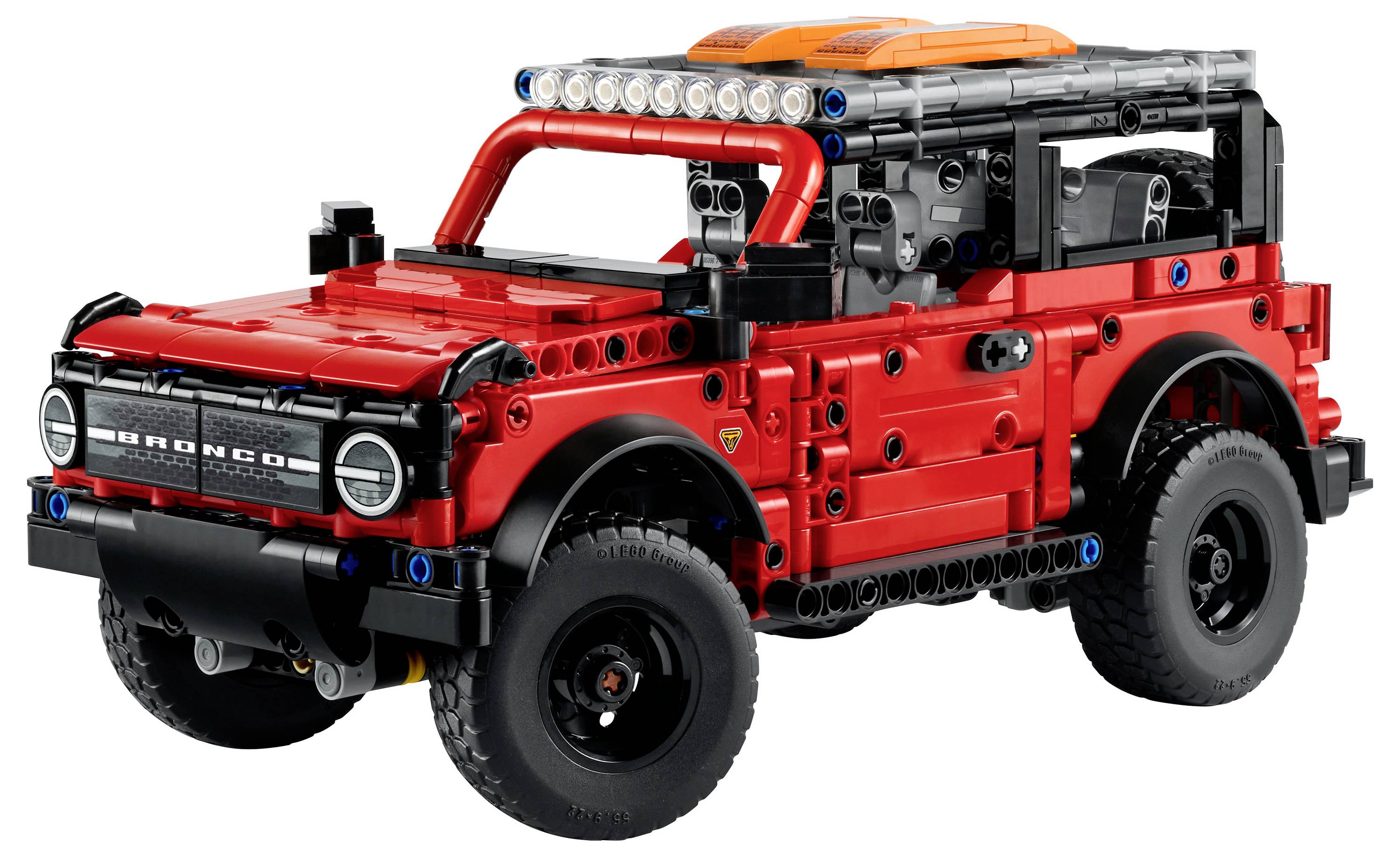 Model terénního vozidla značky LEGO Technic v červené barvě, připomínající Jeep, s precizním designem včetně předních světel, velkých pneumatik a střešního nosiče.