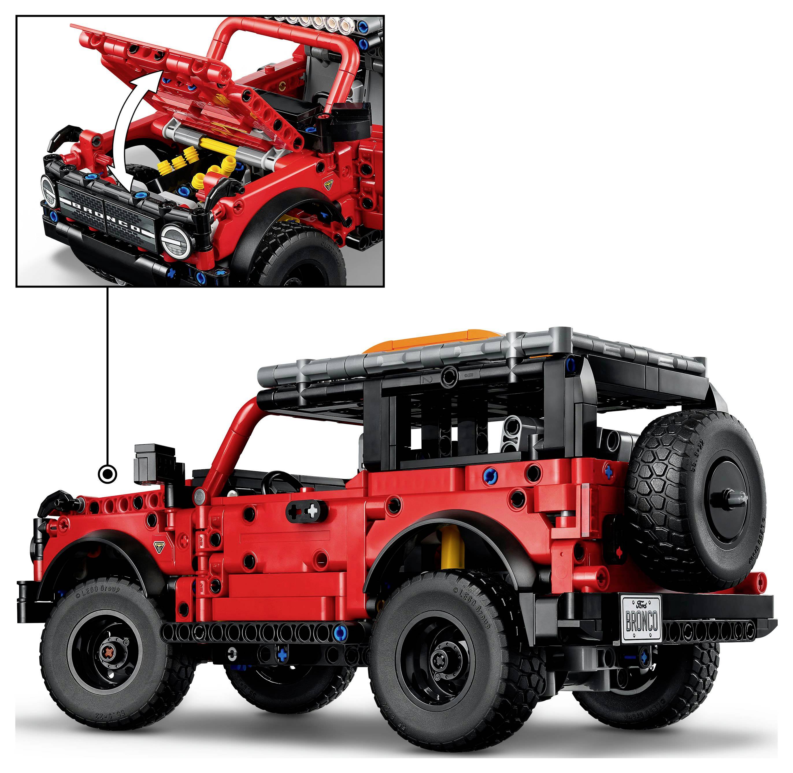 Model LEGO červeného Jeepu s viditelnými detaily motoru, velkými pneumatikami a náhradním kolem umístěným vzadu.