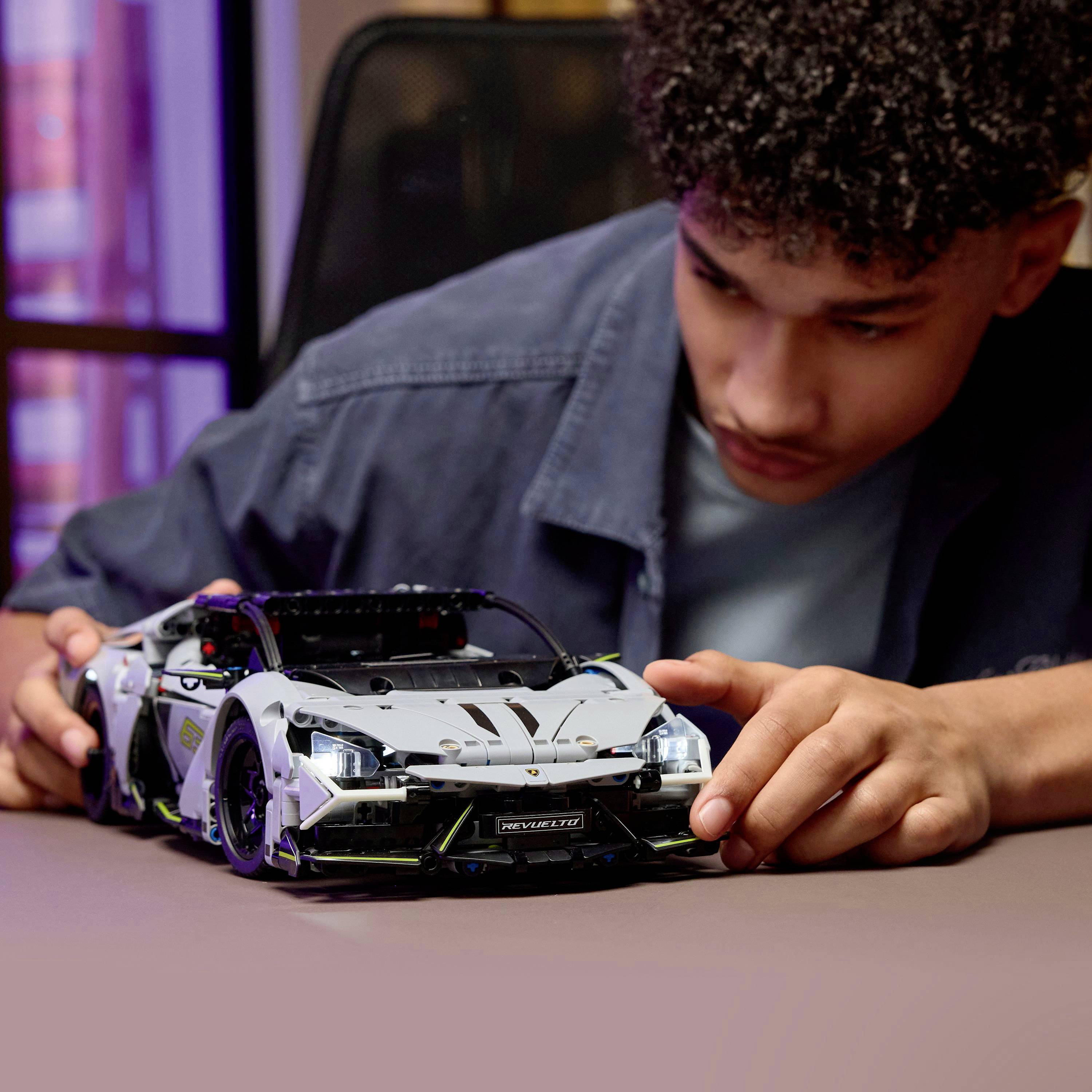 Osoba se soustředěně věnuje sestavování detailního modelu závodního automobilu na stole, přičemž prokazuje mimořádné soustředění a zájem o modelářství.