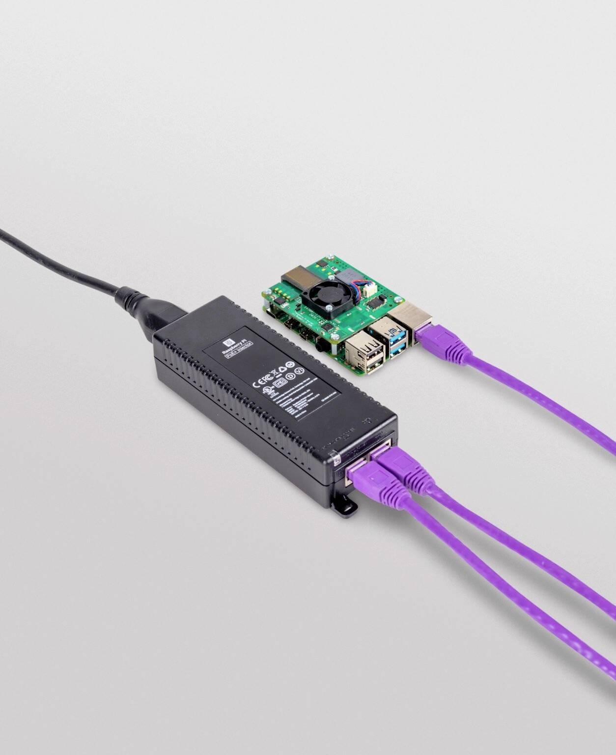Kabelové propojení mezi malým počítačovým čipem a adaptérem. Čip má USB porty, adaptér je připojen k elektrickému napájení.