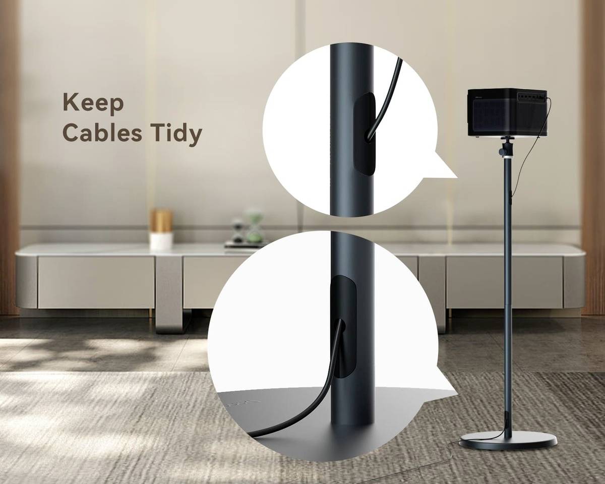 Stojan na monitor s integrovaným systémem vedení kabelů, který pomáhá udržet kabely uspořádané. V pozadí moderní, minimalistický obývací pokoj.