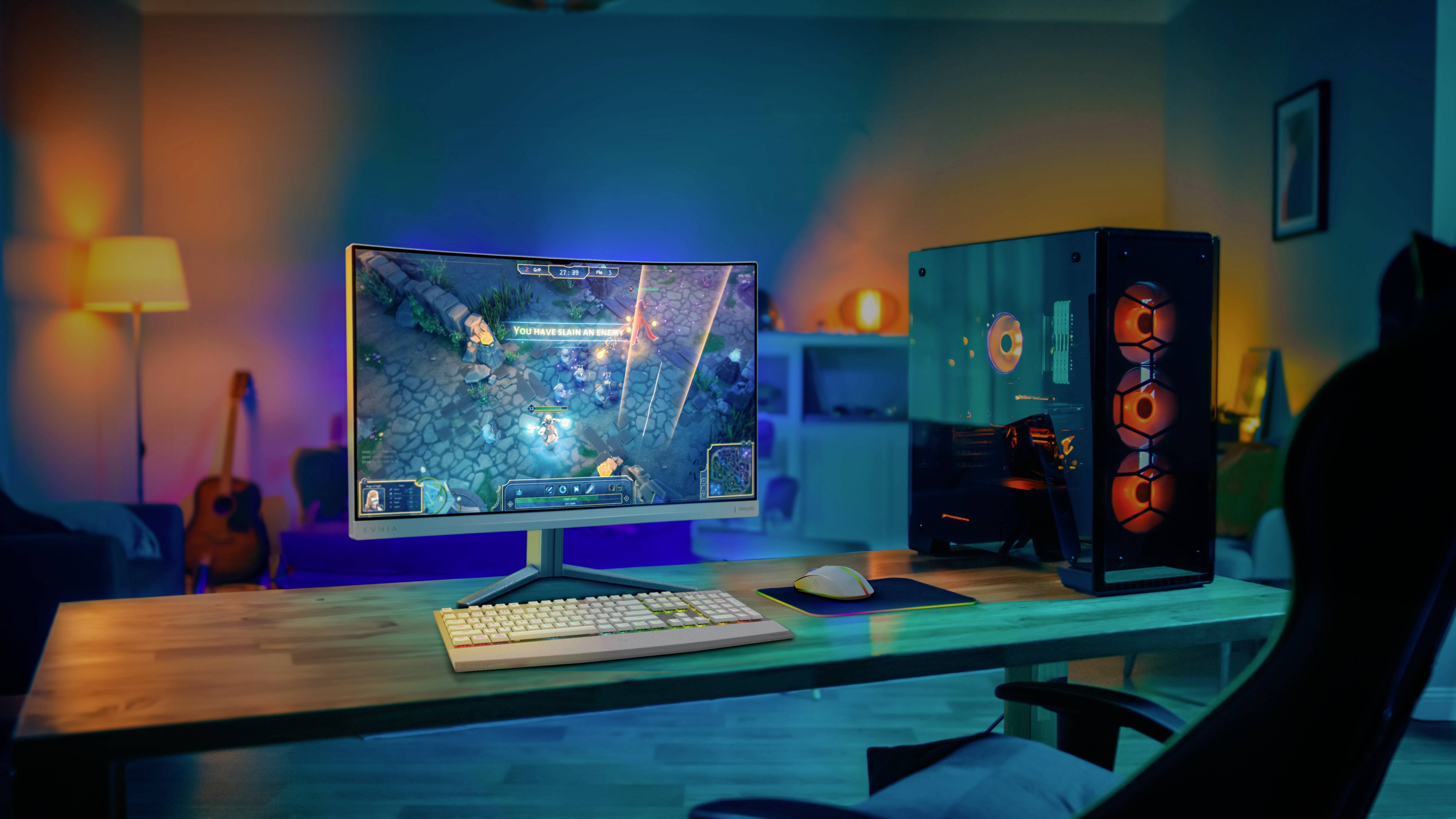 Moderní herní počítač a monitor na psacím stole v útulně osvětlené místnosti. Na obrazovce běží videohra.