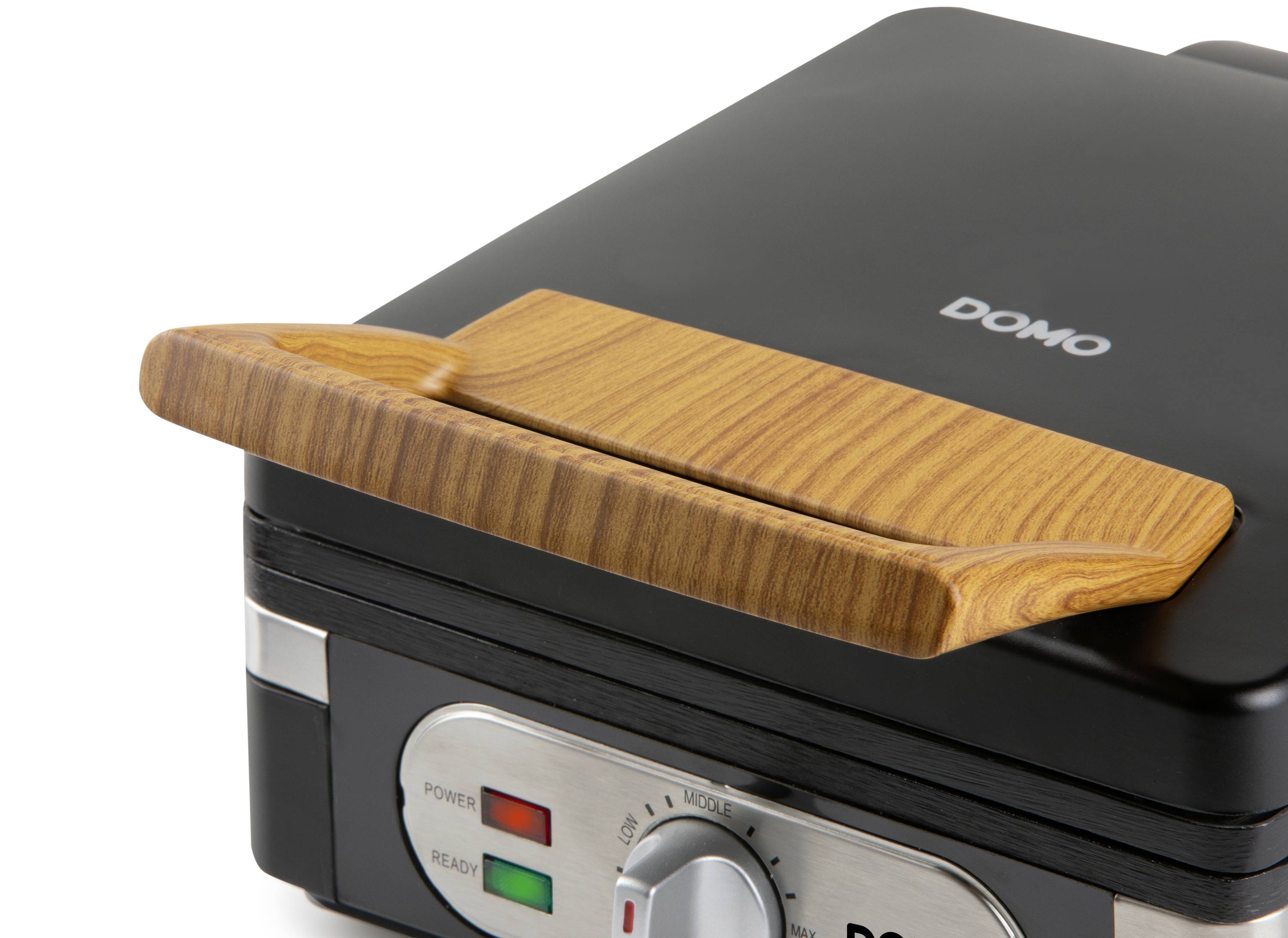 Černá vaflovač se dřevěnou rukojetí, značky 'DOMO', zobrazuje červené a zelené kontrolky pro indikaci napájení a provozní připravenosti.