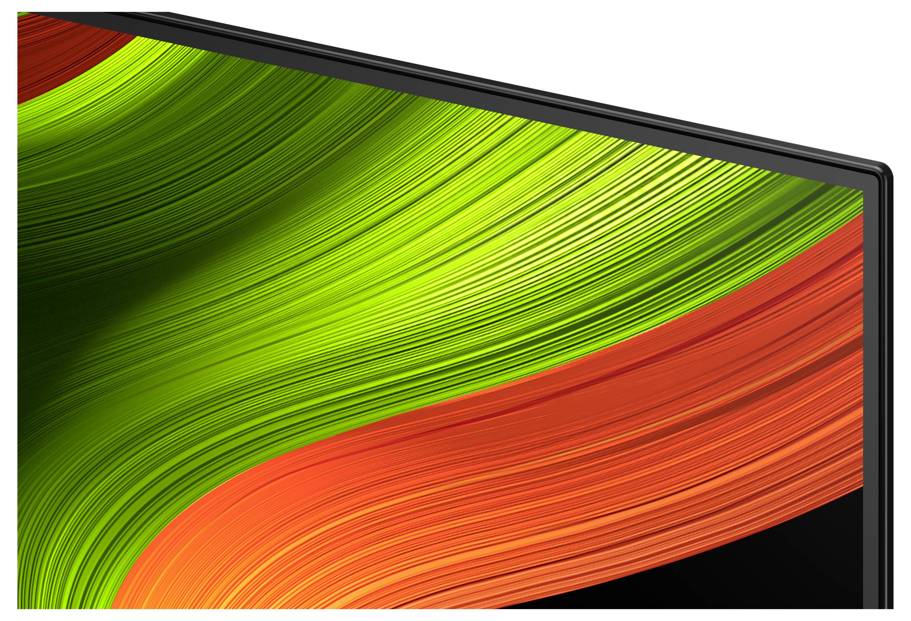 Detailní záběr rohu monitoru zobrazující živý abstraktní design s proudícími zelenými a oranžovými tahy.
