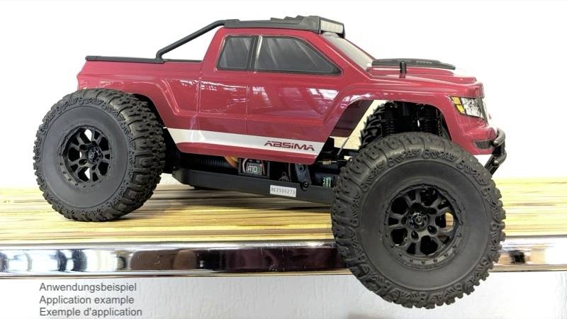 Červené rádiem řízené modelové auto s velkými, robustními pneumatikami stojí na dřevěné desce. Text zobrazuje 'Příklad použití'.