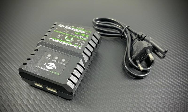 Nabíječka se dvěma USB porty a síťovým kabelem leží na černém povrchu.