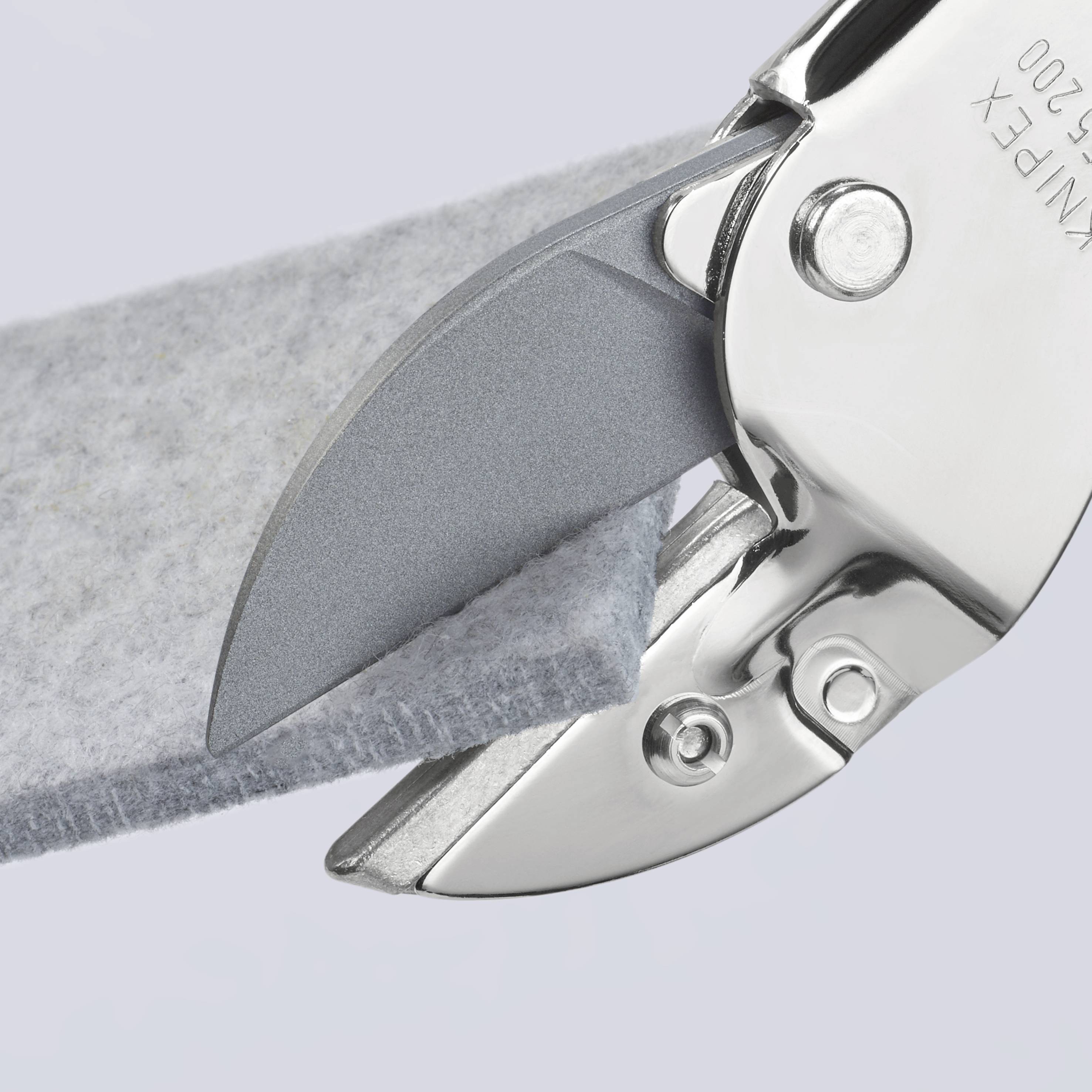 Detailní záběr ostrých nůžek, které střihají kus šedého plstěného materiálu. Čepel je vyrobena z lesklého kovu.