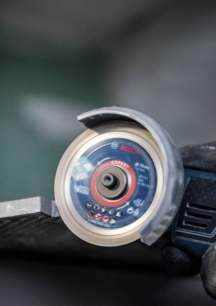 Bruska obrábí kovovou hranu, bez jiskření. Zaměření na rotující brusný kotouč při práci.