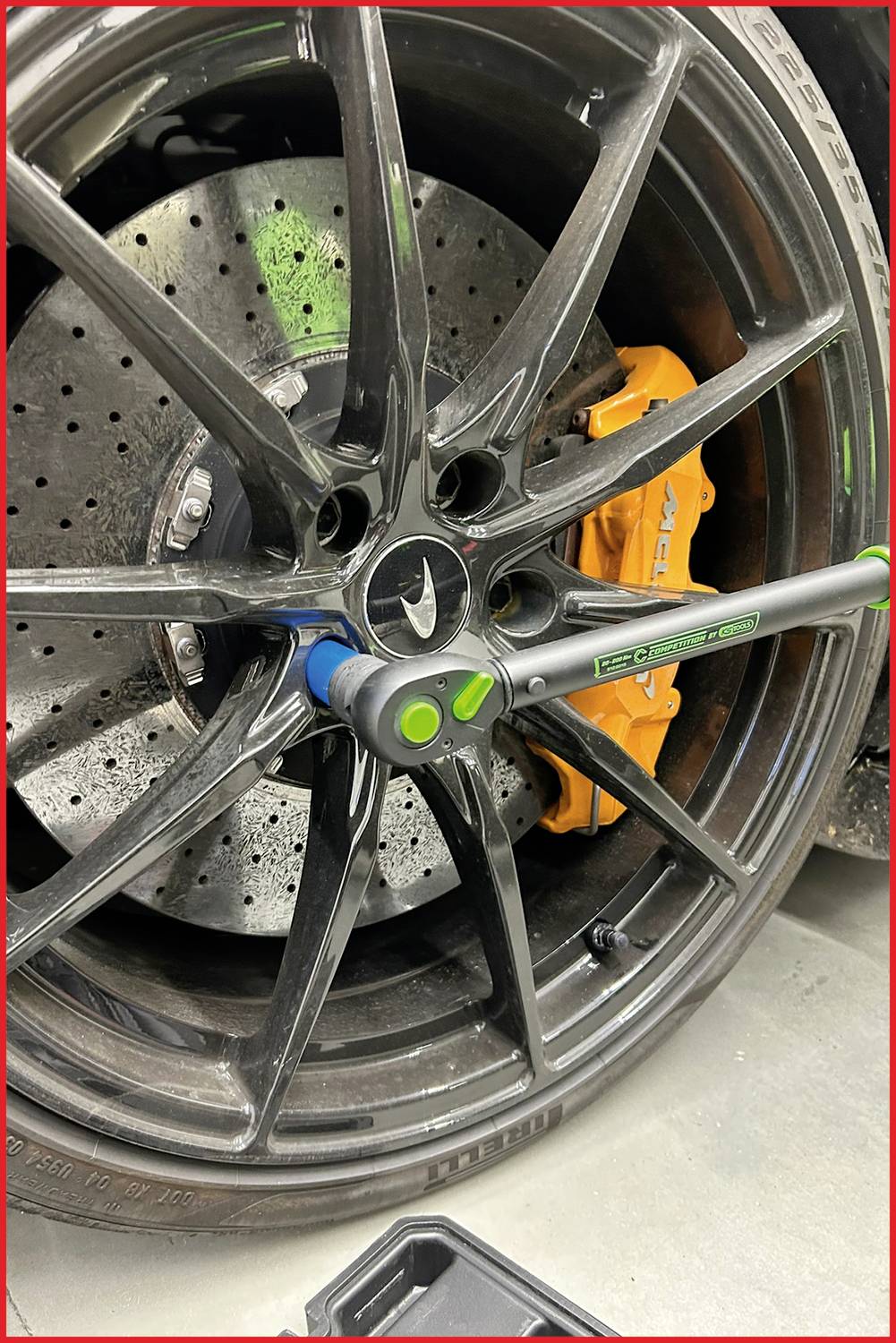 Automobilový plášť s brzdovým kotoučem a třmenem. Momentový klíč je nasazen na kolovou matici, připravený na výměnu pneumatiky.