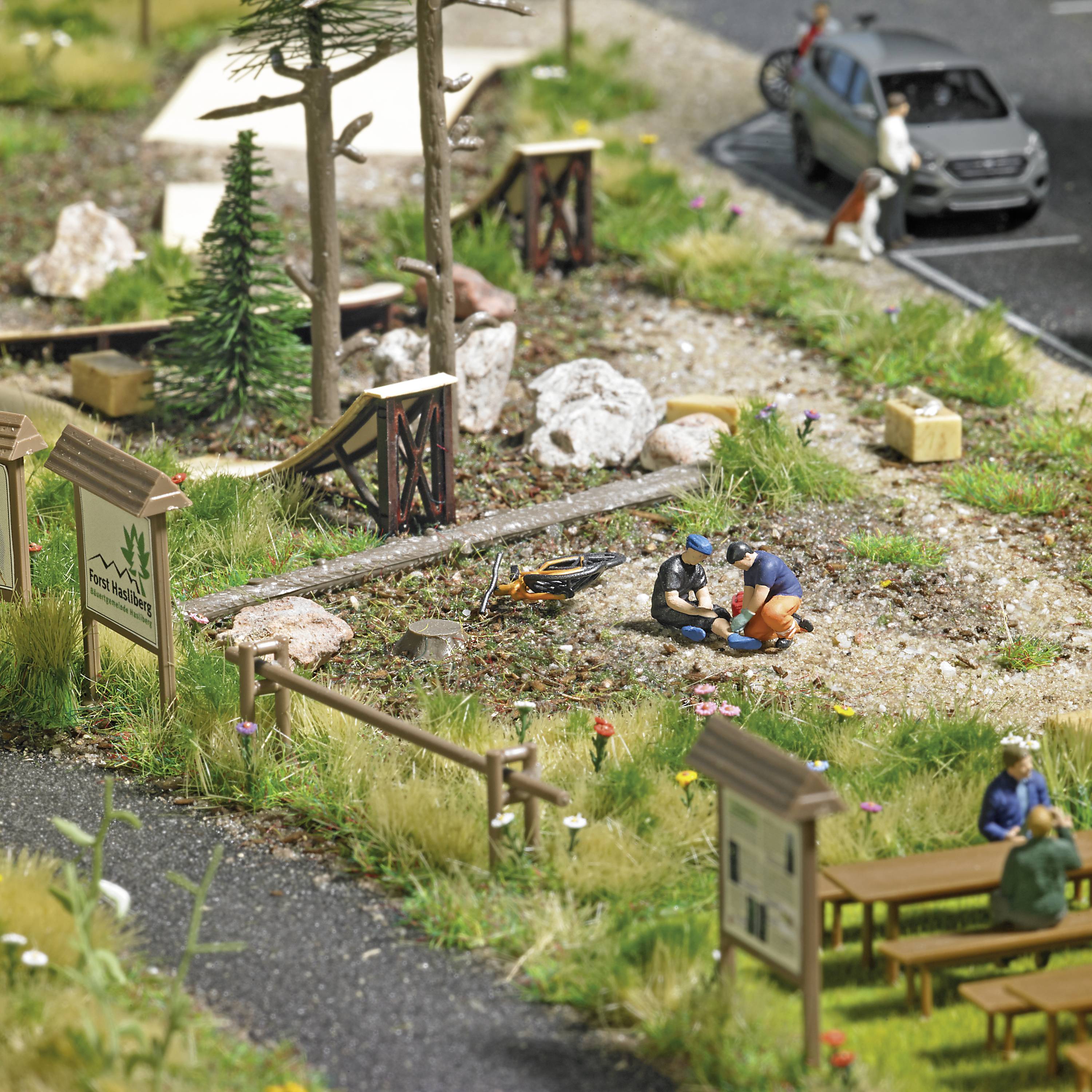 Miniaturní diorama zobrazuje parkovou scénu s lidmi, stromy a rybníkem. Dvě postavy uprostřed jsou ponořeny do hovoru.