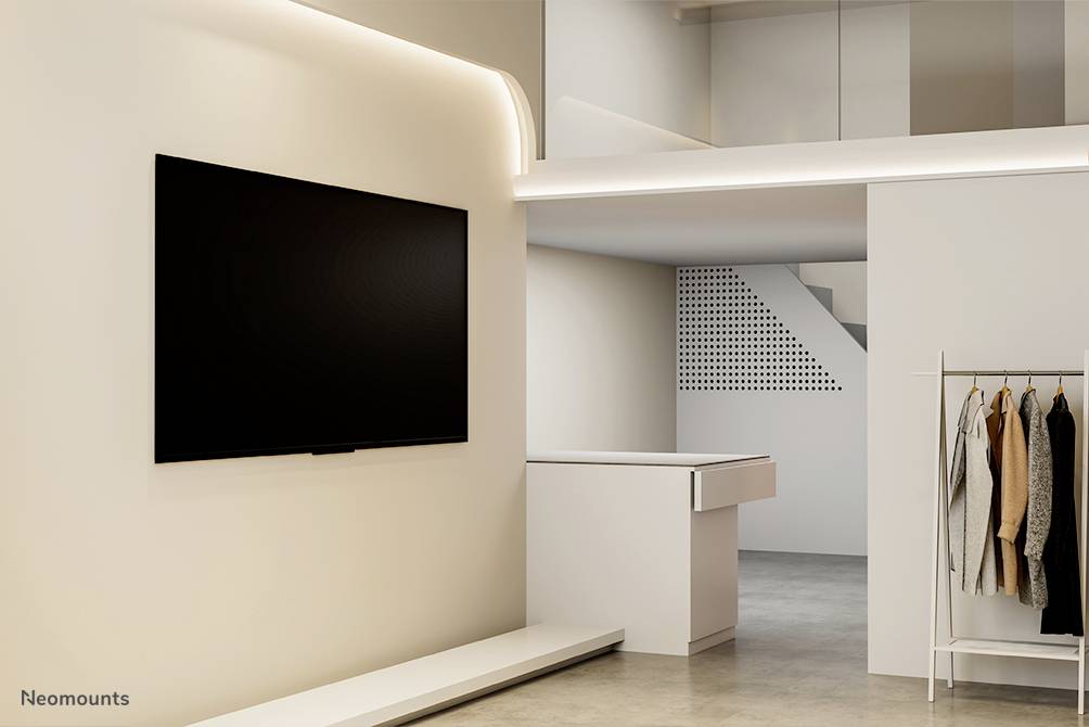 Moderní, minimalistický pokoj s velkým televizorem zavěšeným na stěně, šatní skříní a jednoduchou světelnou výbavou.