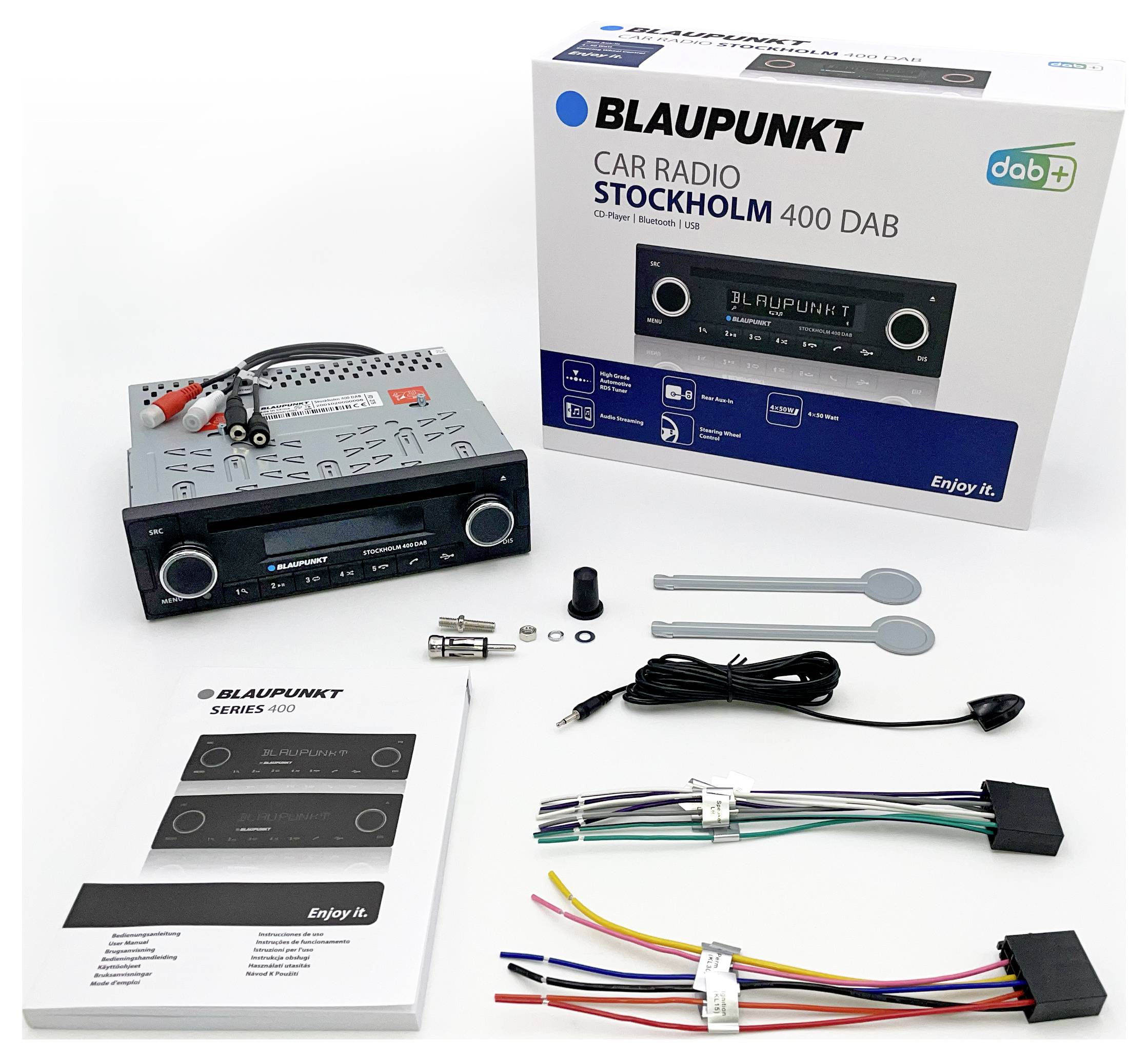Autorádio Blaupunkt Stockholm 400 DAB s příslušenstvím včetně kabelů, návodu a montážního nářadí, rozložené na stole.