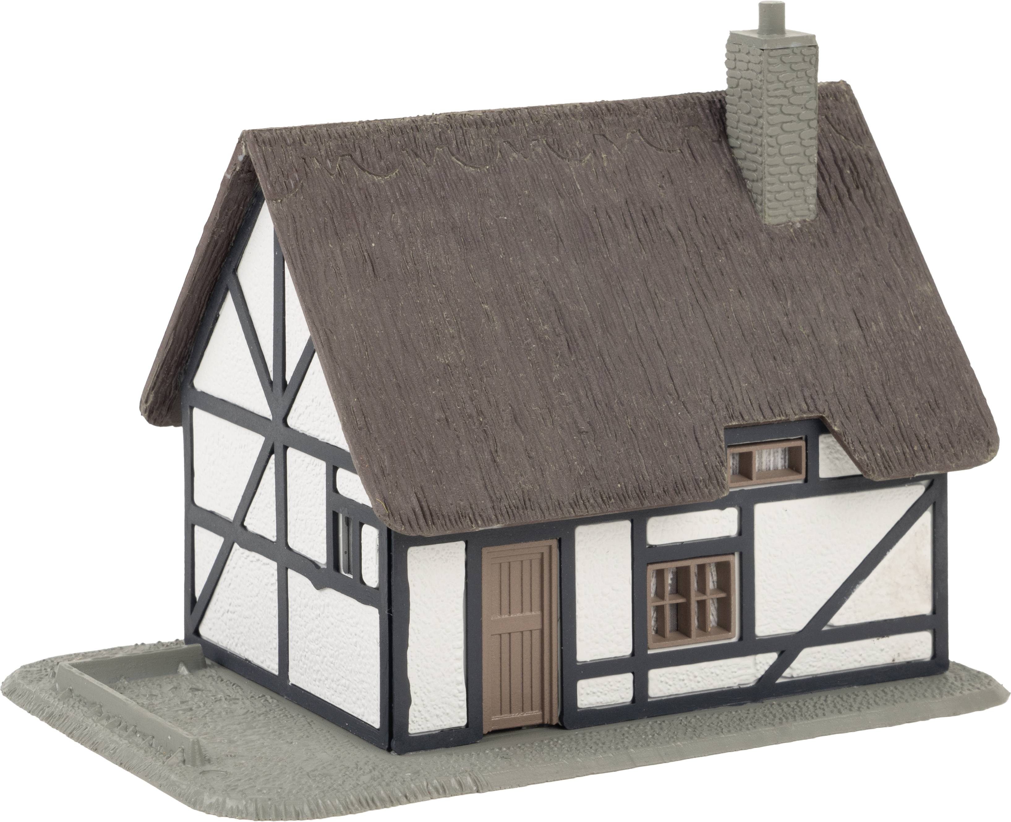Malý modelový dům ve venkovském hrázděném stylu se slaměnou střechou a komínem, typický pro venkovskou architekturu.