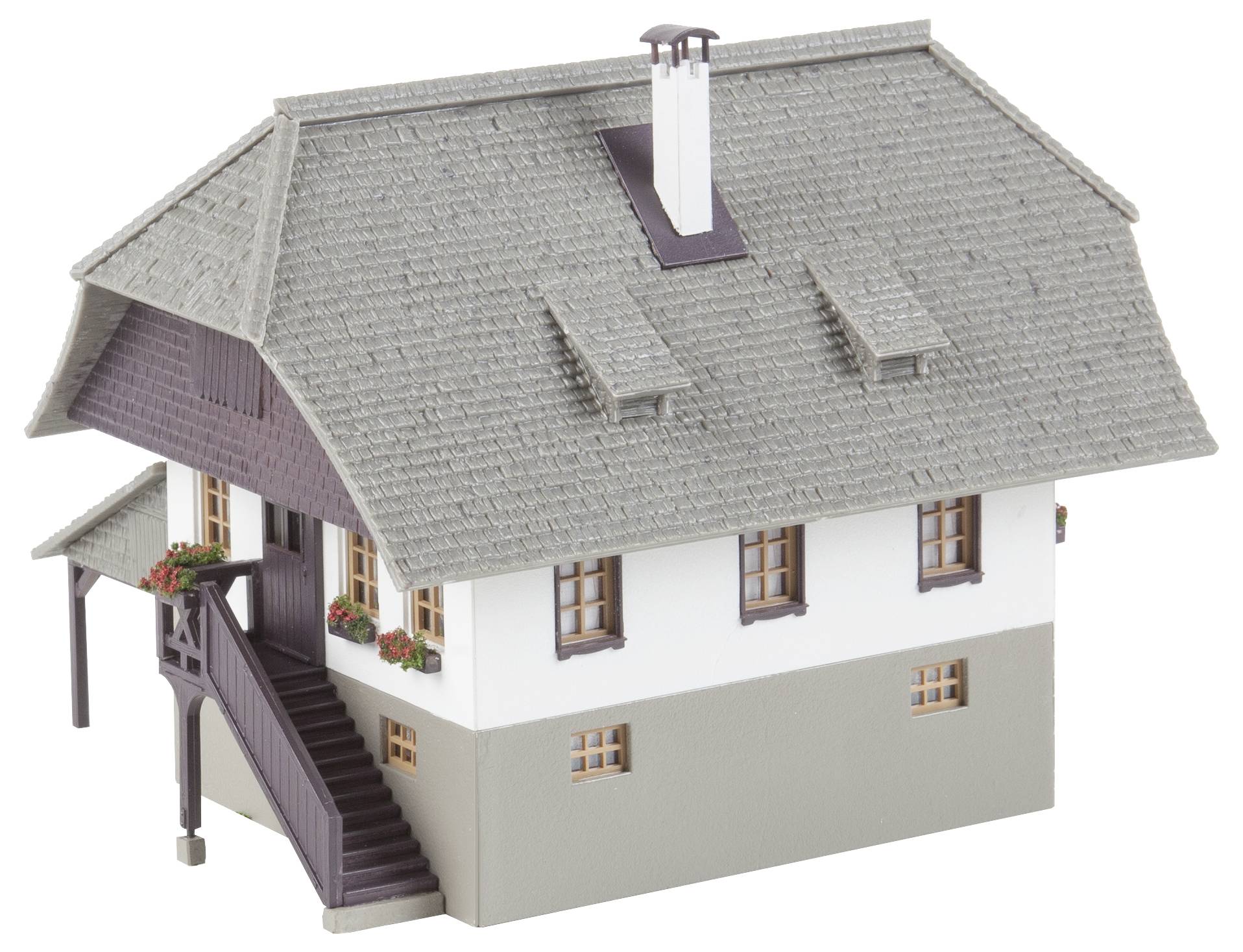 Model tradičního domu se šedou šindelovou střechou, bílými stěnami a dřevěnými ozdobami. Schodiště vede ke vchodu.