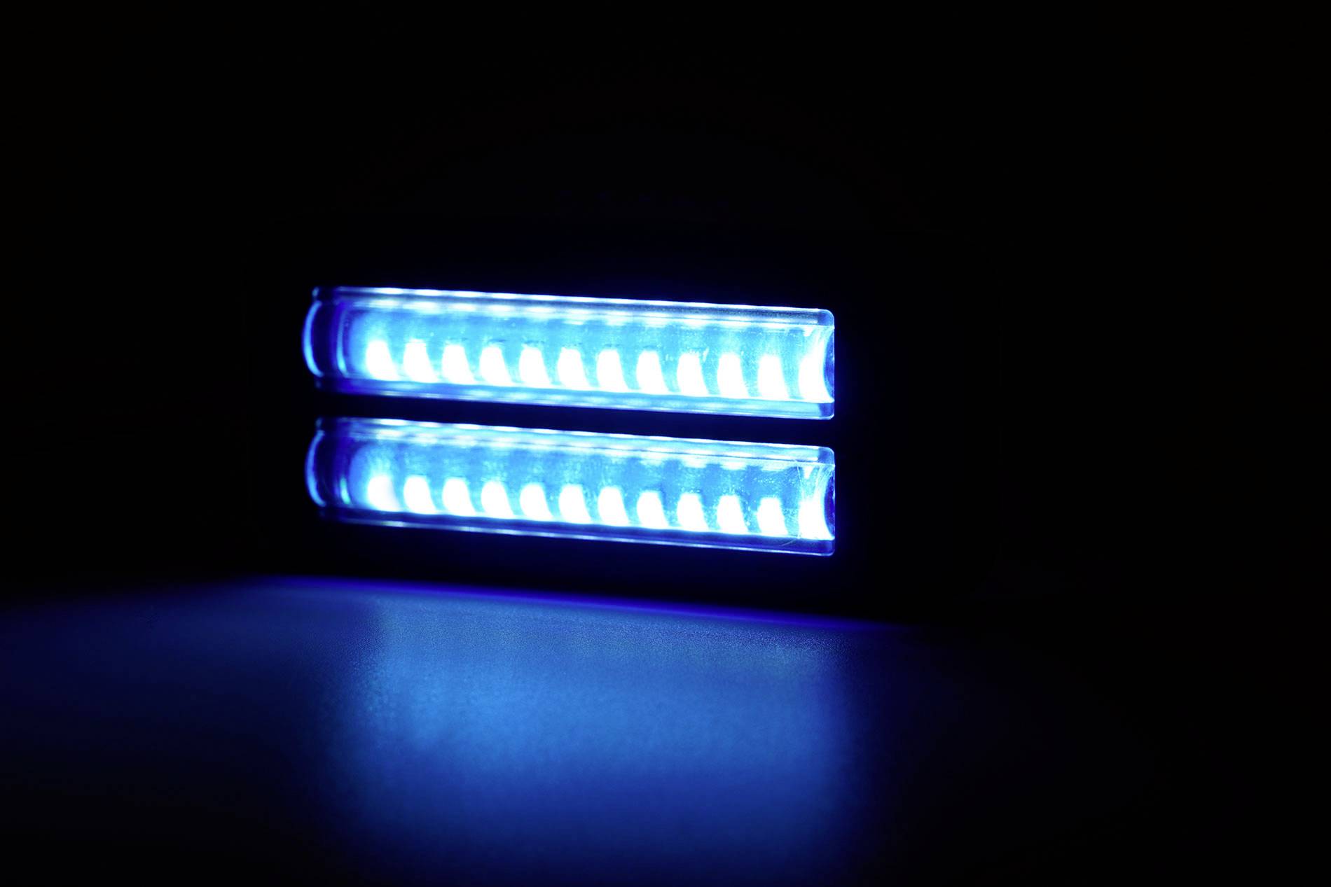 Zářící modrá LED lampa v tmavé místnosti, skládající se ze dvou rovnoběžných pruhů.