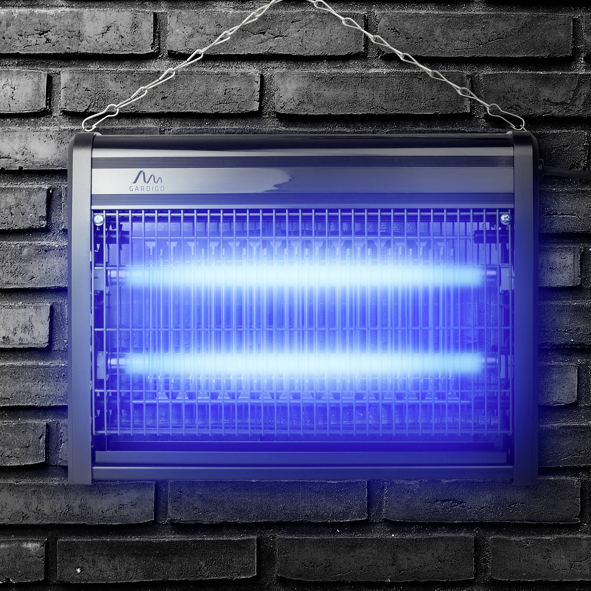Elektrický hubič hmyzu s modrým UV světlem zavěšený na cihlové zdi, určený k likvidaci létajícího hmyzu.