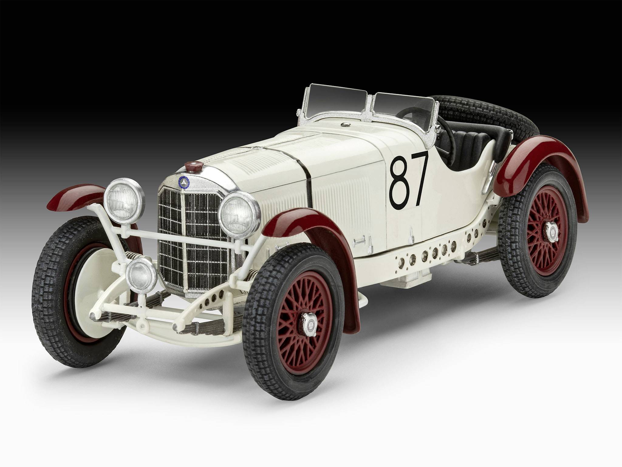 Klasický závodní vůz s červeným a bílým designem karoserie, startovní číslo '87'. Ukázka historického automobilového designu.
