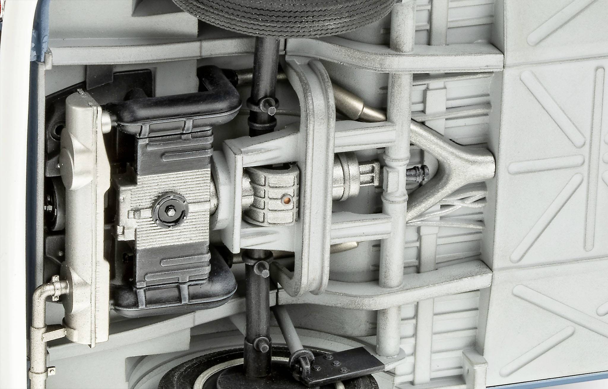 Spodní pohled na detailní vozidlovou nápravu a zavěšení s tlumiči pérování, hnacím ústrojím a různými mechanickými komponenty.