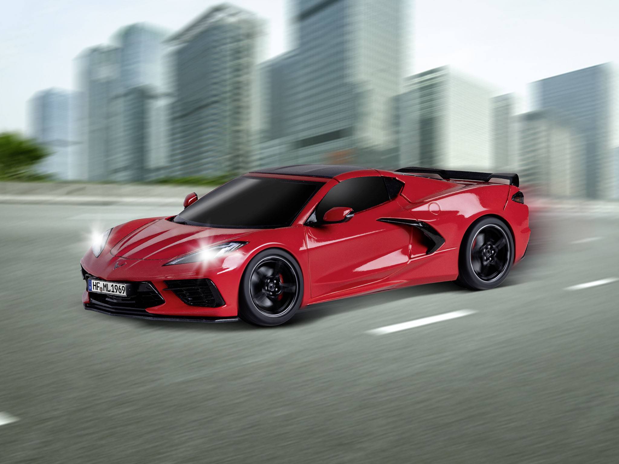 Červené sportovní auto jede po silnici před rozostřeným pozadím mrakodrapů.