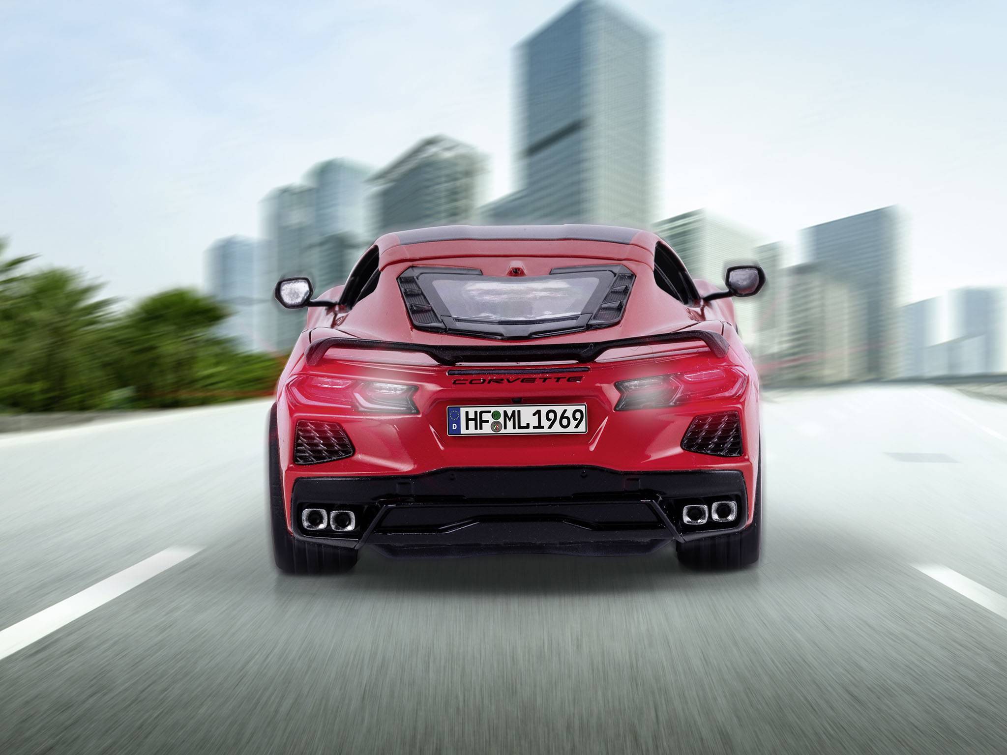 Červené sportovní auto jede po prázdné městské ulici. V pozadí jsou rozmazané mrakodrapy.