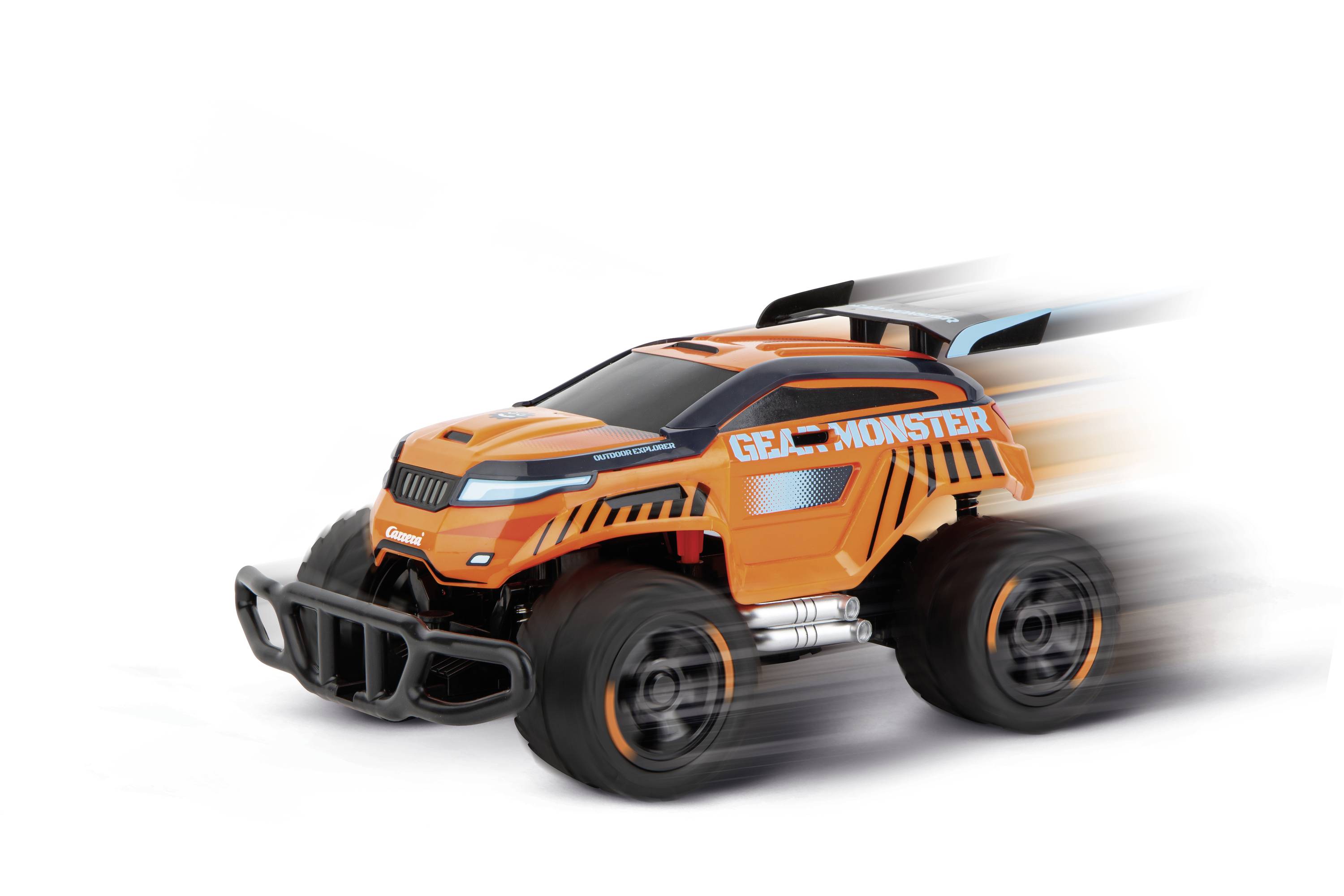 Oranžové hračkářské auto v závodním designu se rychle pohybuje doprava. Na autě je nápis 'GEAR MONSTER'.