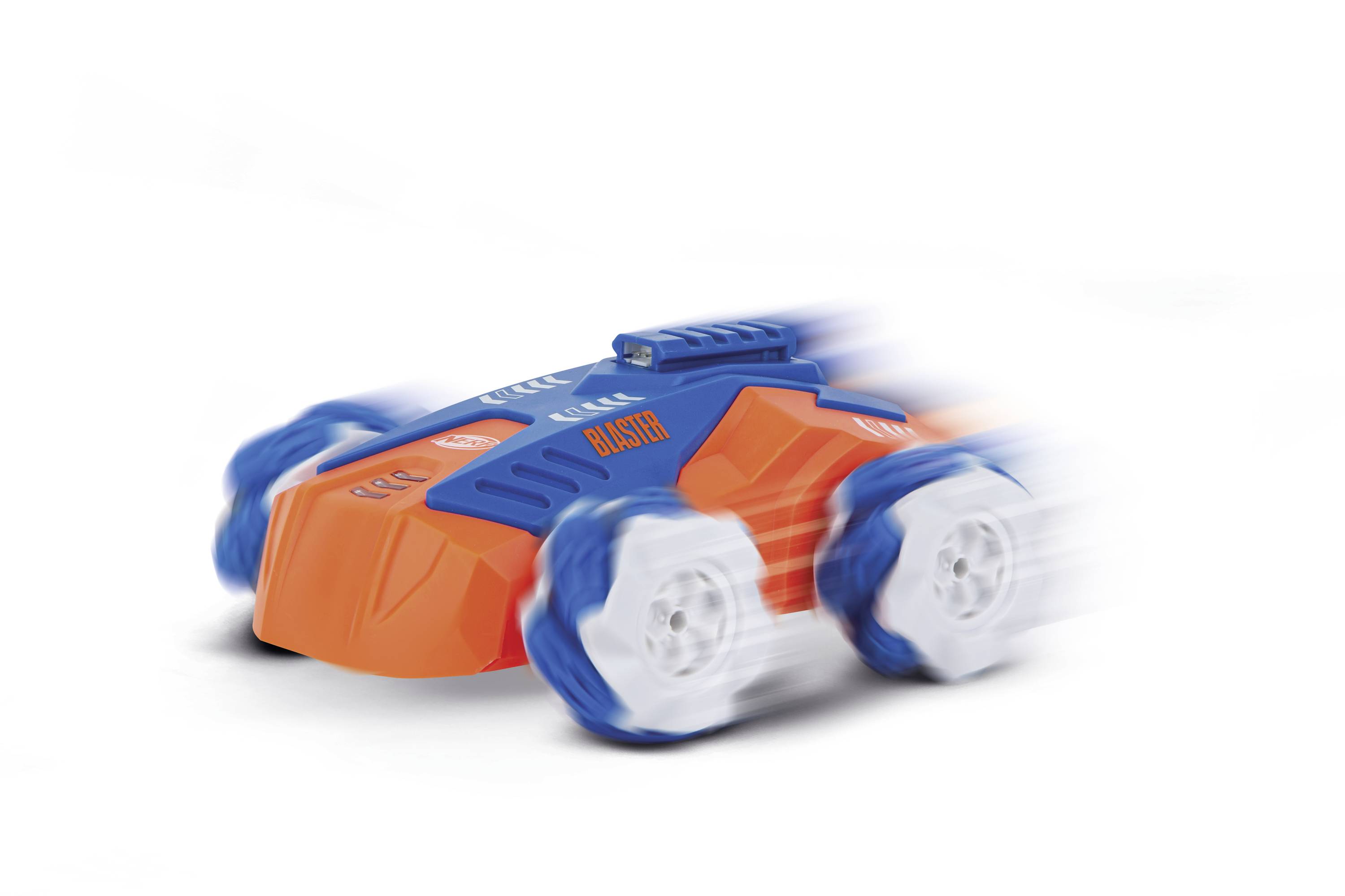 Oranžovo-modré hračkářské auto s nápisem 'Blaster' rychle jede doleva, přičemž kola vykazují rozmazání pohybu.