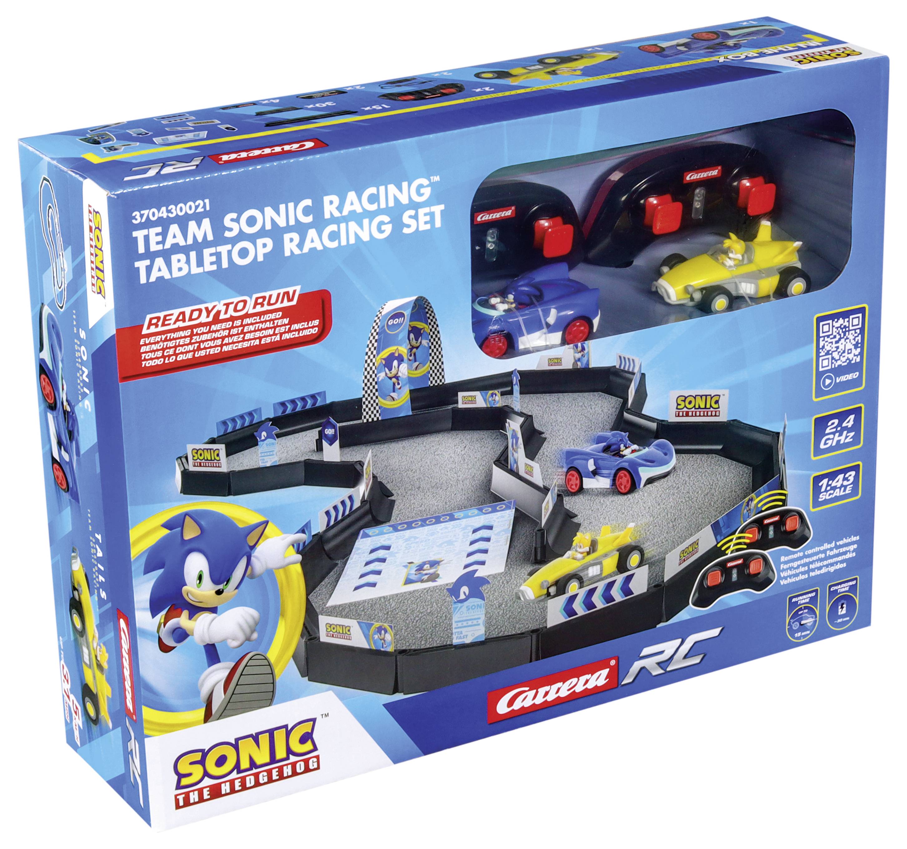 Hračkářská závodní dráha 'Týmové Sonic Racing - Stolní závodní sada' se dvěma závodními vozy a figurkou Sonica. Obal ukazuje trať a vozidla.