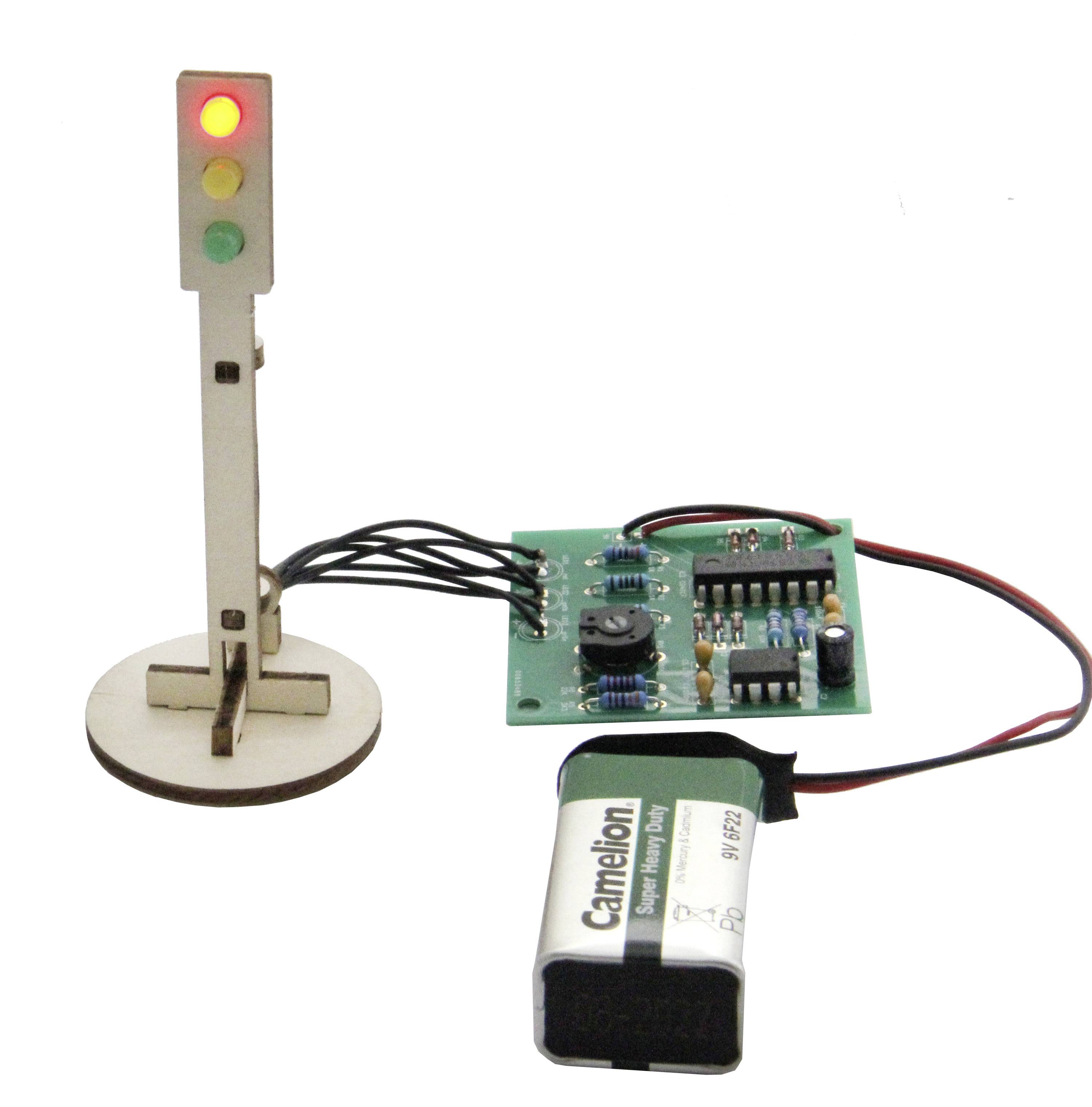Miniaturní replika semaforu s elektrickým obvodem a baterií, přičemž svítí červené světlo.